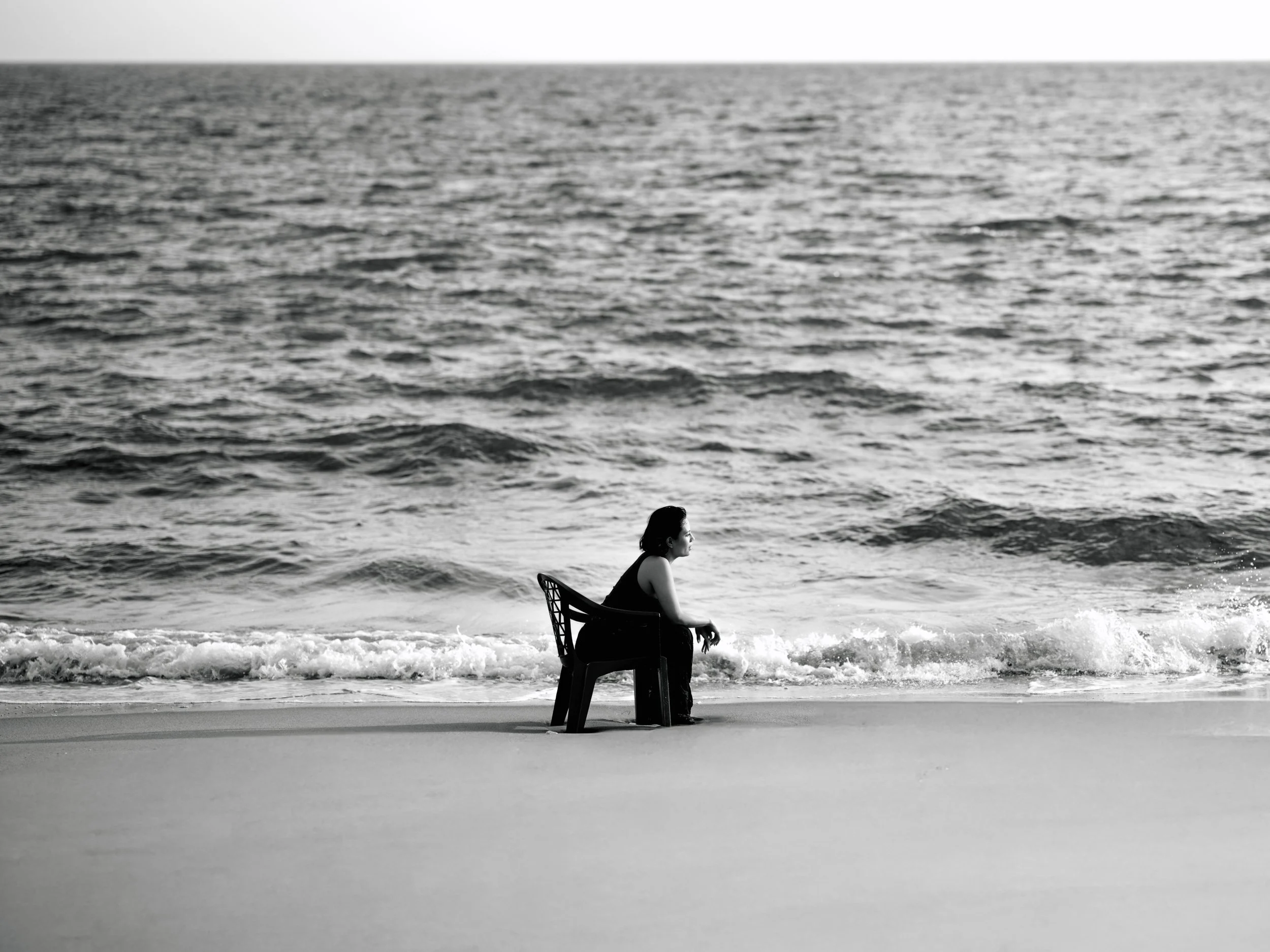 Shaina Rae seated on a chair in the surf, black and white