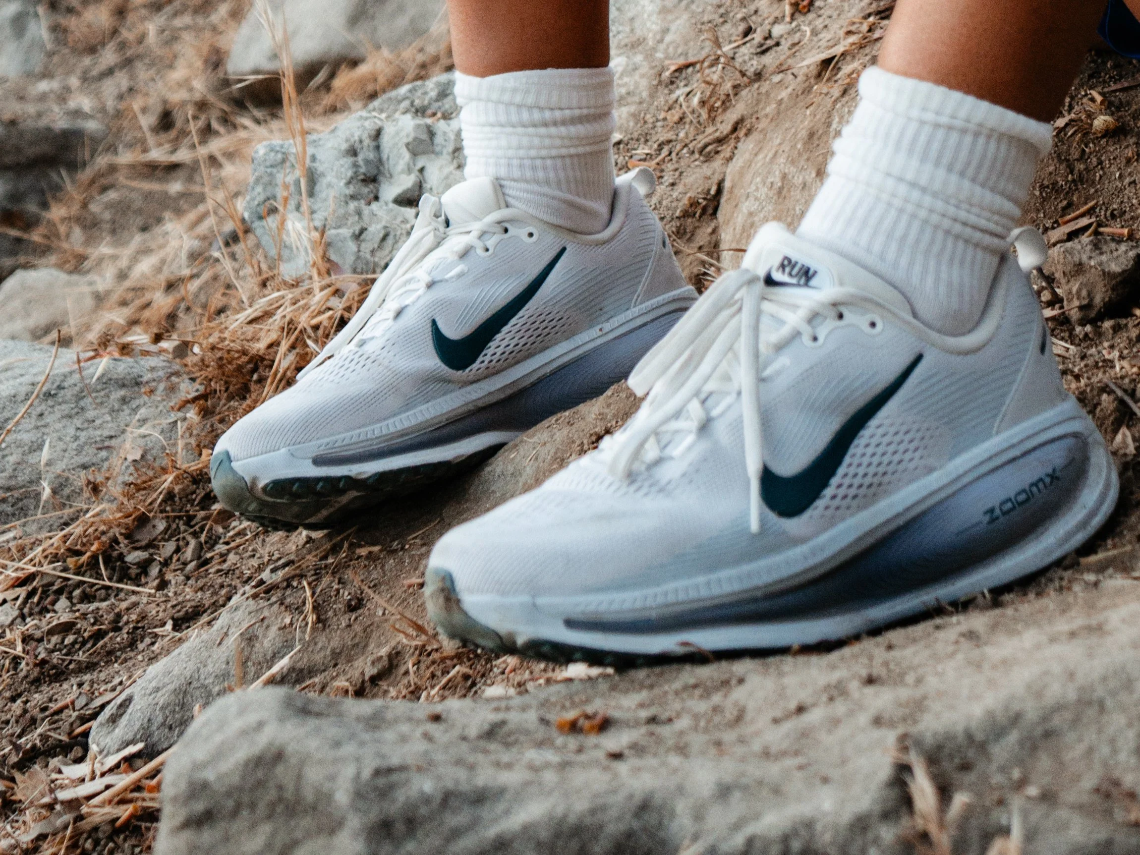 Close-up of white Nike running shoes on rocks