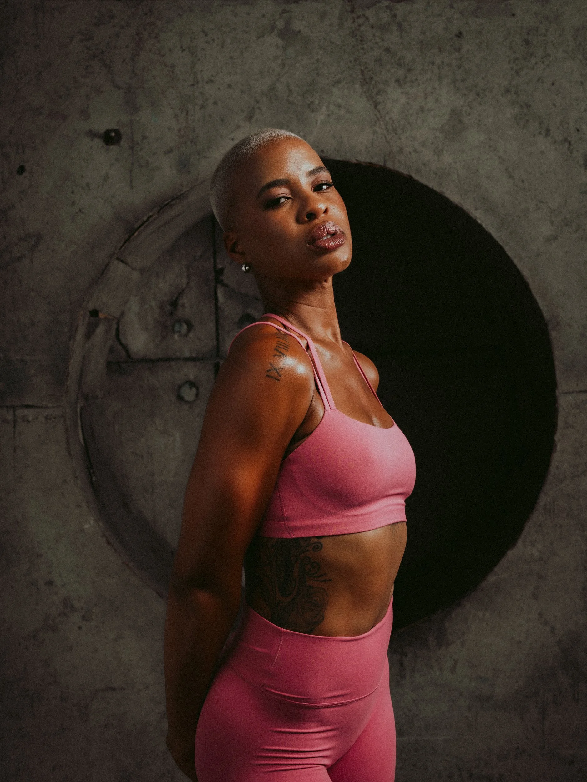 Athlete in pink activewear posing in front of a circular concrete doorway