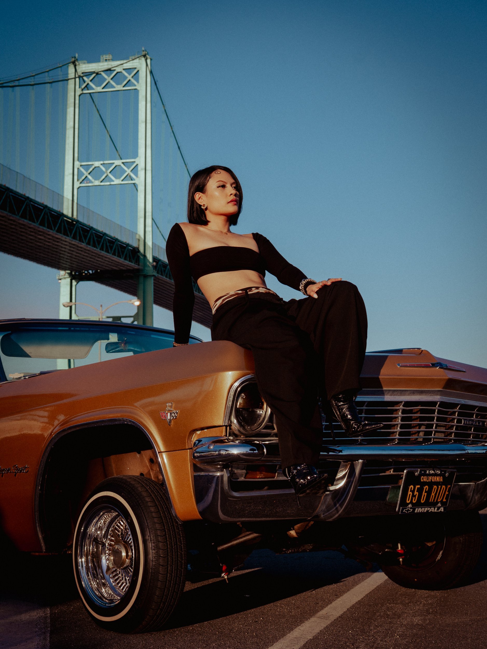 Shaina Rae sitting on a copper lowrider under a bridge, lifestyle photography