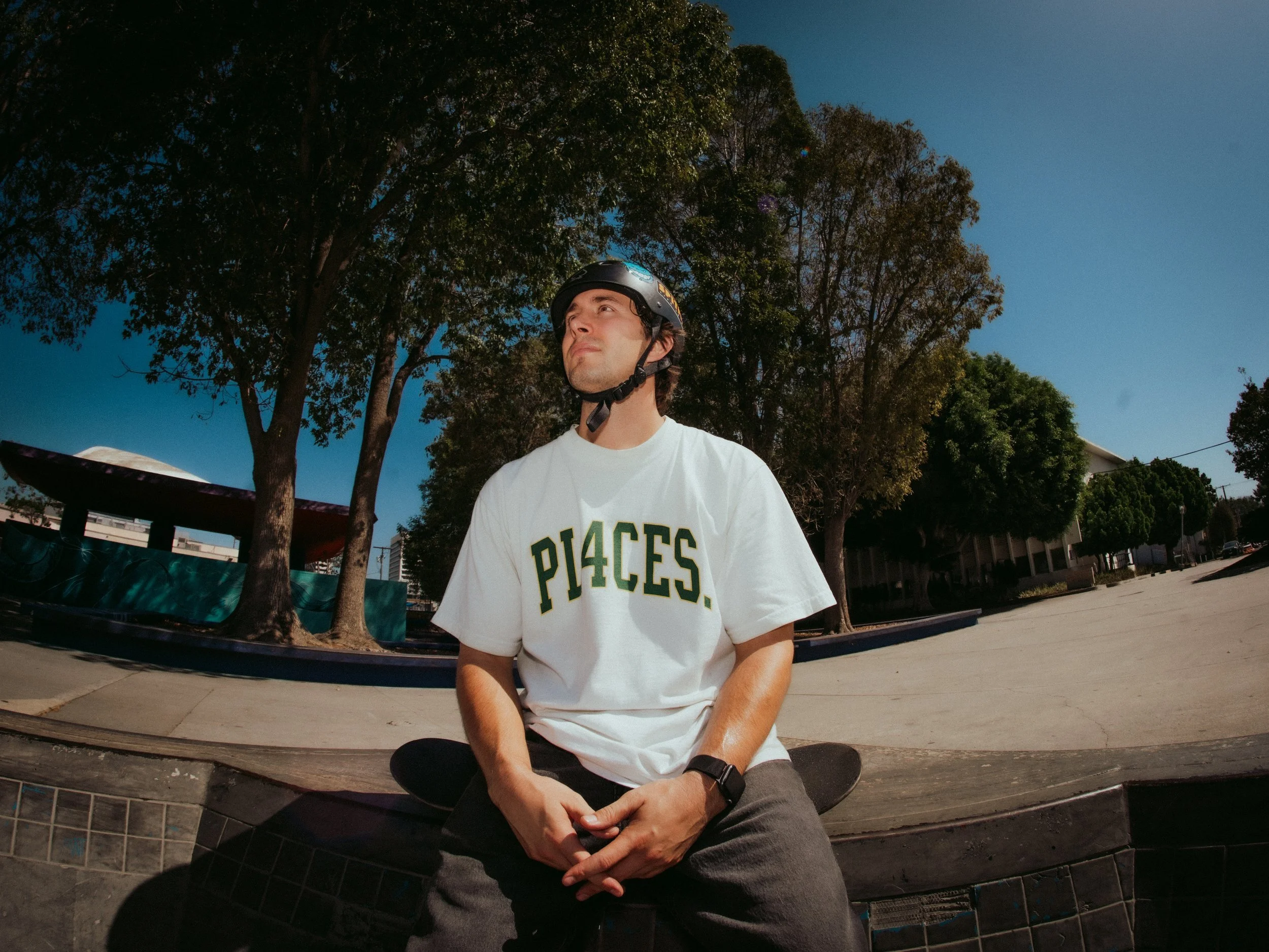 Brandon Loufas seated with his board in a PL4CES tee at the West LA Courthouse skatepark, Los Angeles skate photography by Osy Ikhile