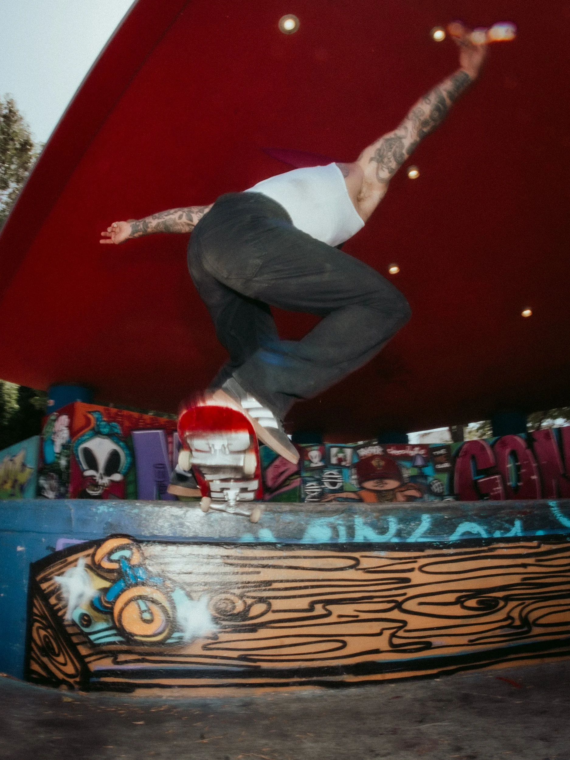 Skater grinding the red wall above graffiti at the West LA Courthouse skatepark, Los Angeles skate photography by Osy Ikhile