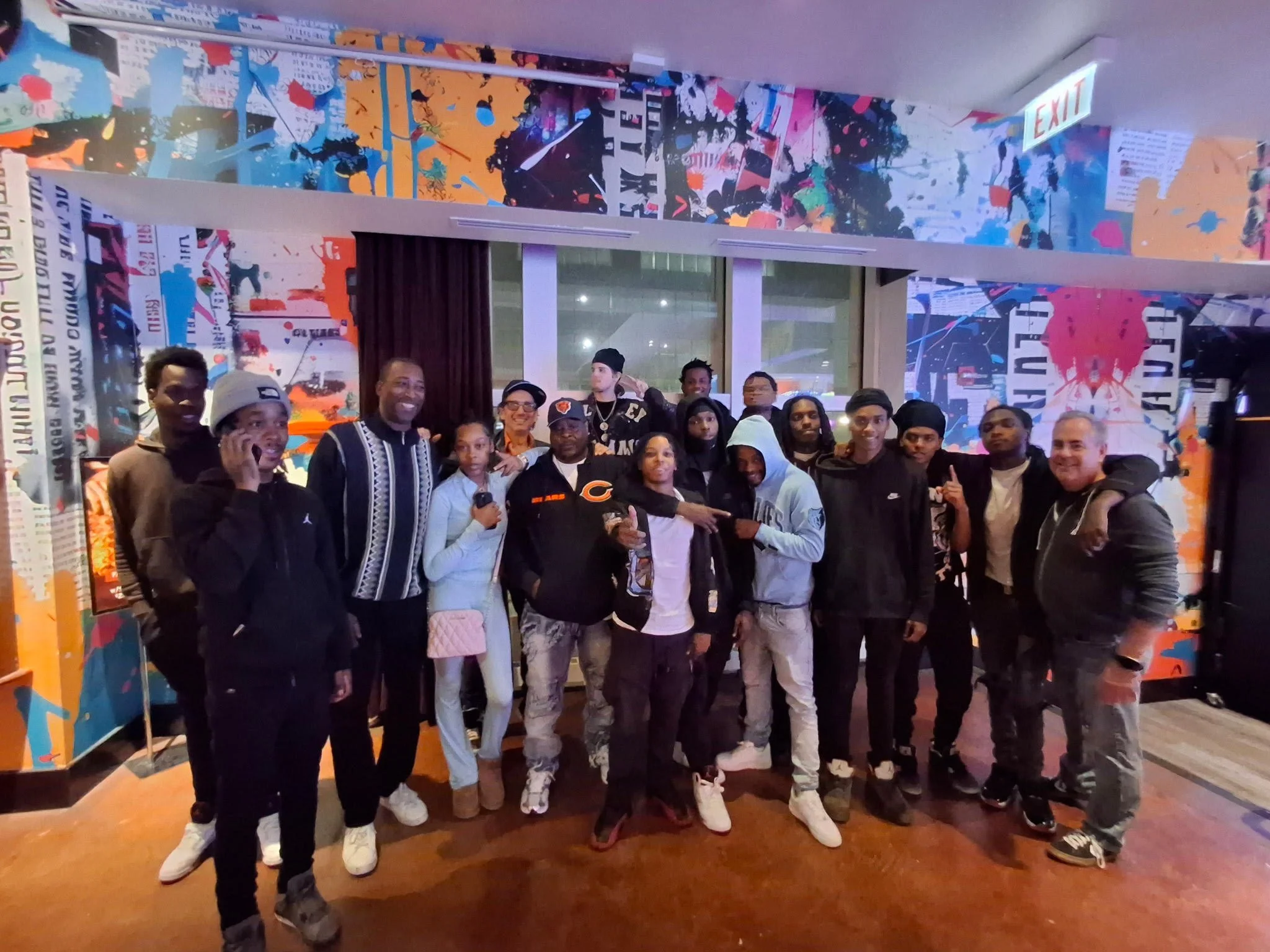 Group of people posing together indoors with colorful abstract artwork on the walls