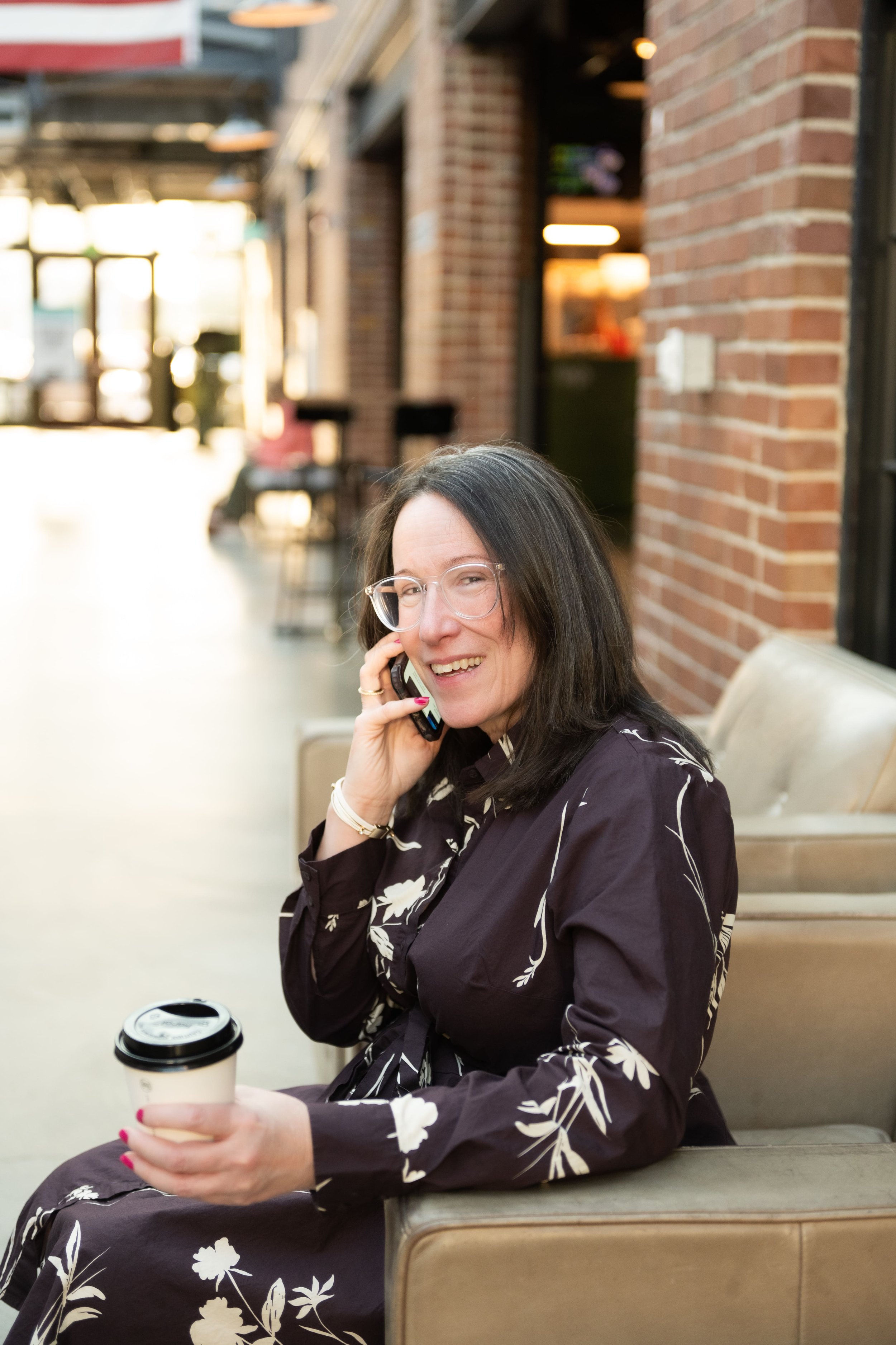 Emily Mendez, mental health content writer, sitting outdoors with coffee while taking a phone call.