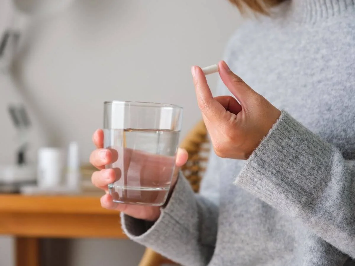 Woman holding a bipolar medication pill and a glass of water.