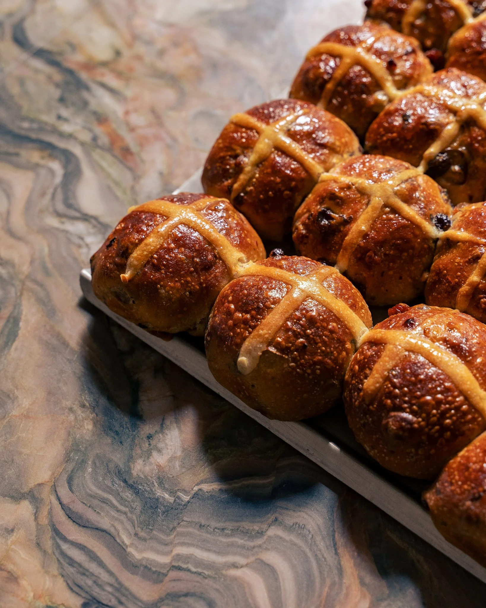 Close-up of glazed meatballs with crisscrossed mustard on top, arranged on a white tray on a marble surface.