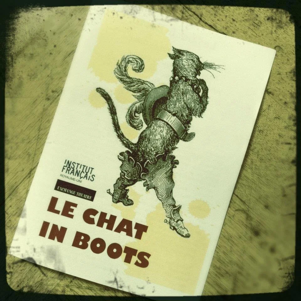 ‘Le Chat in Boots’ program with an illustration of a cat wearing boots, a hat, and a cloak, standing on its hind legs