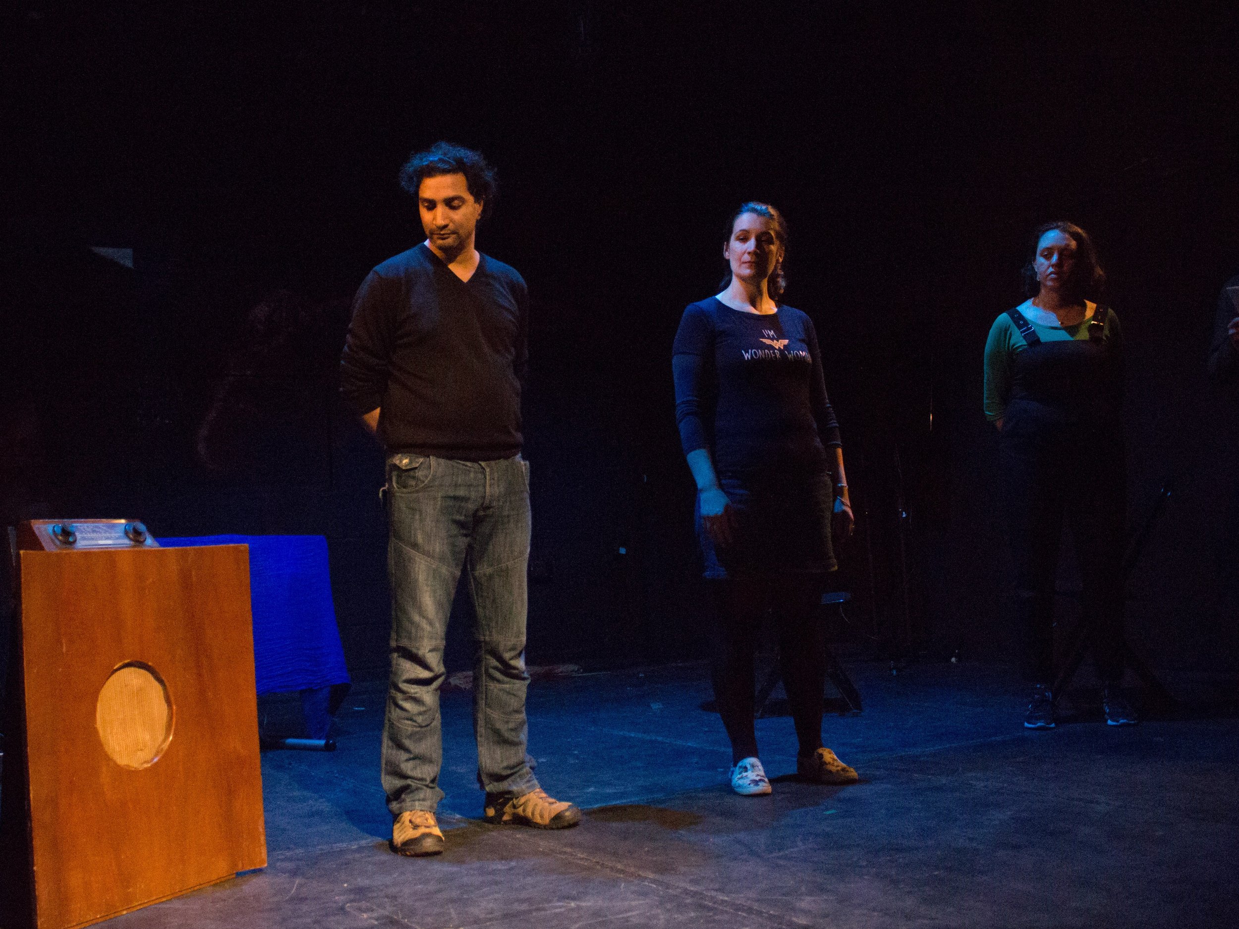 Three people standing on a stage in a dark theater