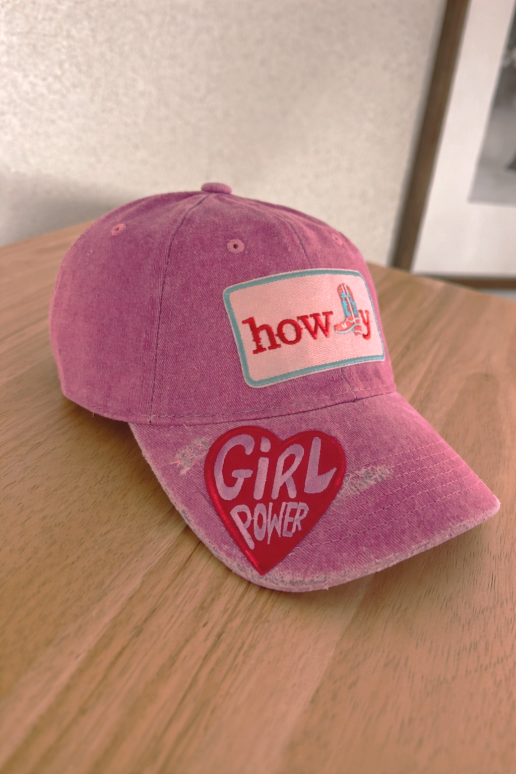 Pink baseball cap with embroidered patches that say "howdy" and "girl power" and feature a roller skate and a heart.
