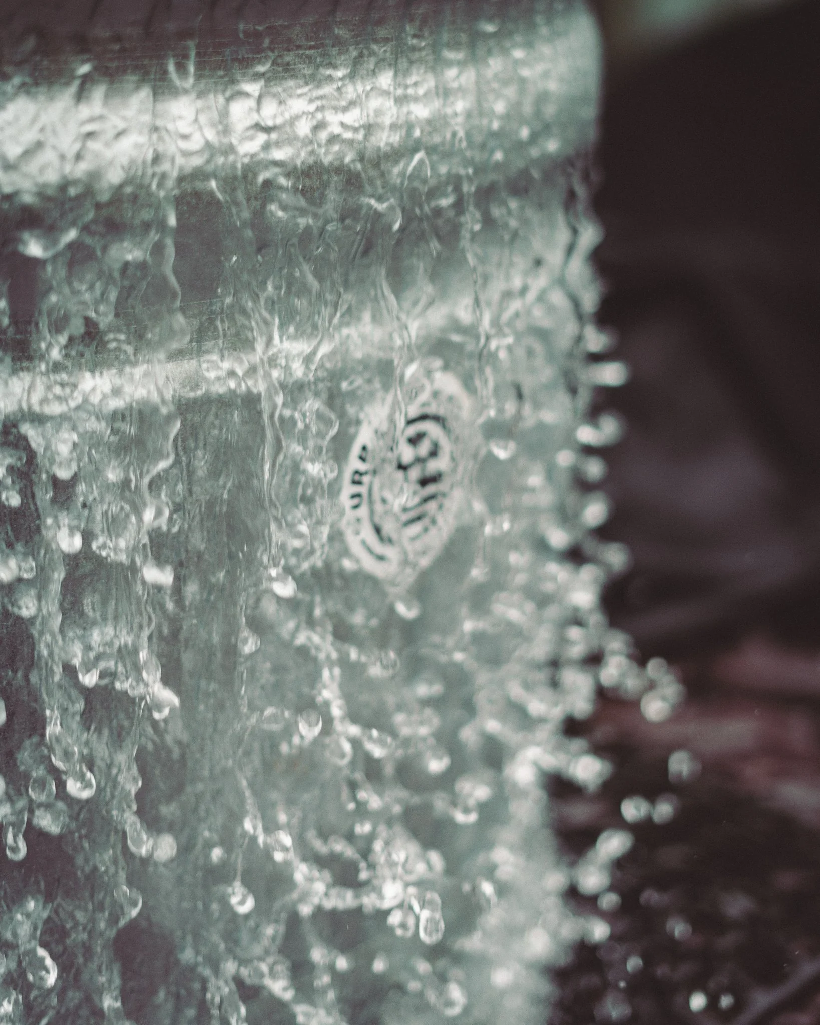 At Unfold Sauna Club Close-up of a water bottle with water splashing and droplets on its surface.