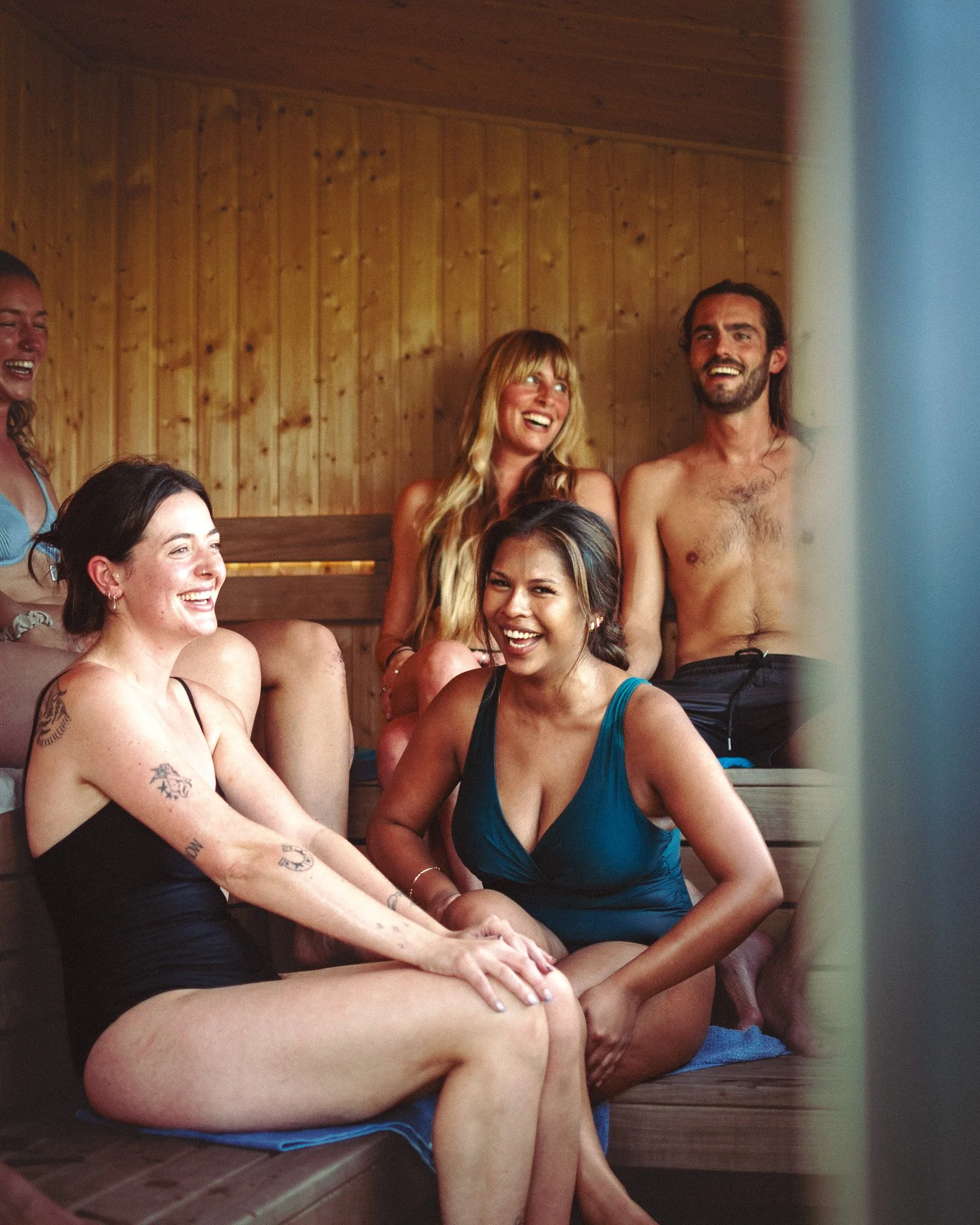 At Unfold Sauna Club Group of friends smiling and laughing together in a wooden sauna or steam room.