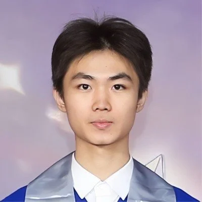 A young man with short black hair, wearing a light gray and blue graduation gown and white shirt, standing in front of a purple background with a star in the distance.