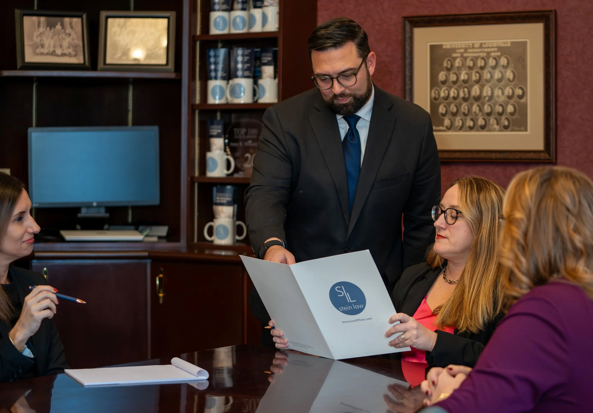 Business meeting in an office with four women and one man in a suit reviewing documents