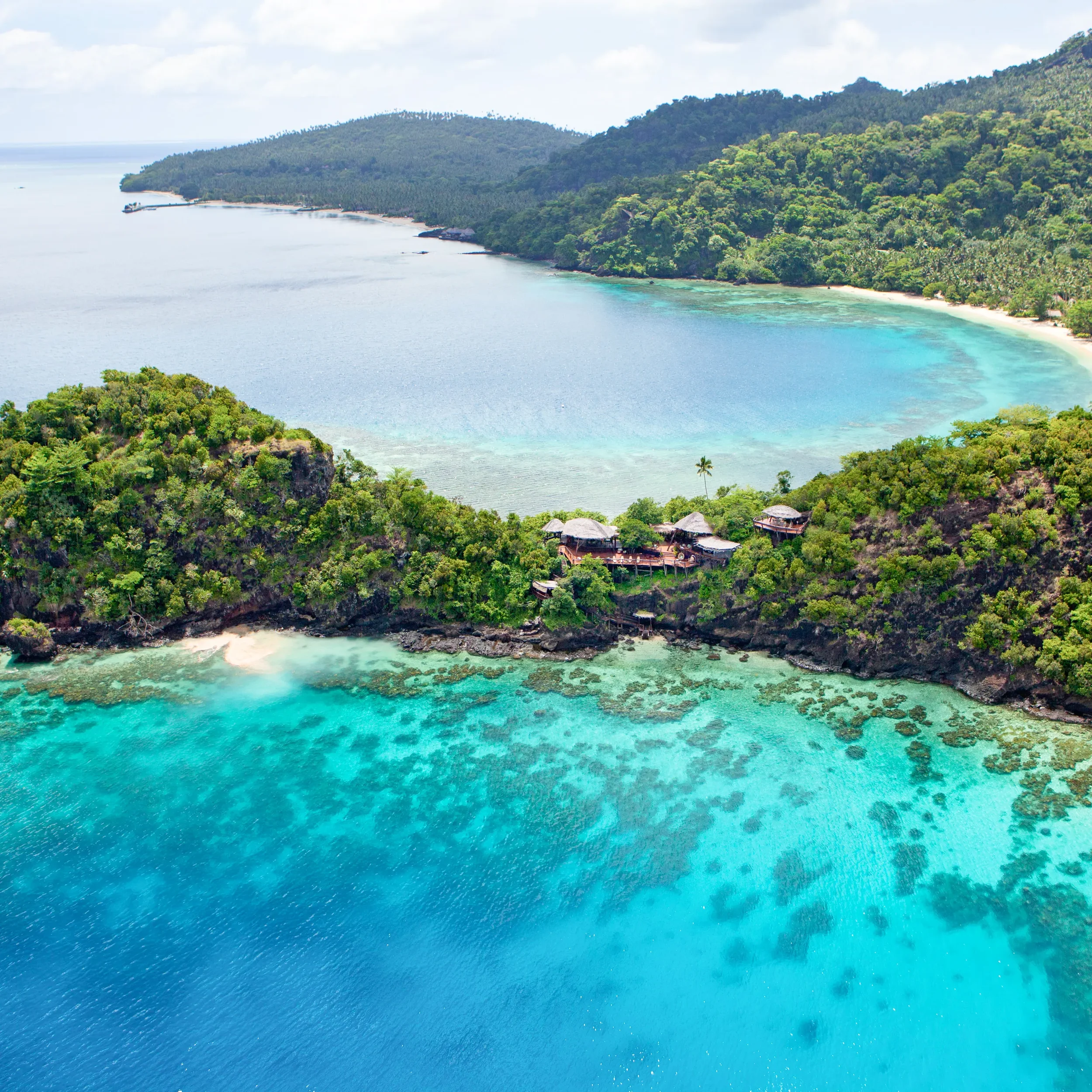 Luxury tropical island resort surrounded by turquoise ocean and lush green coastline