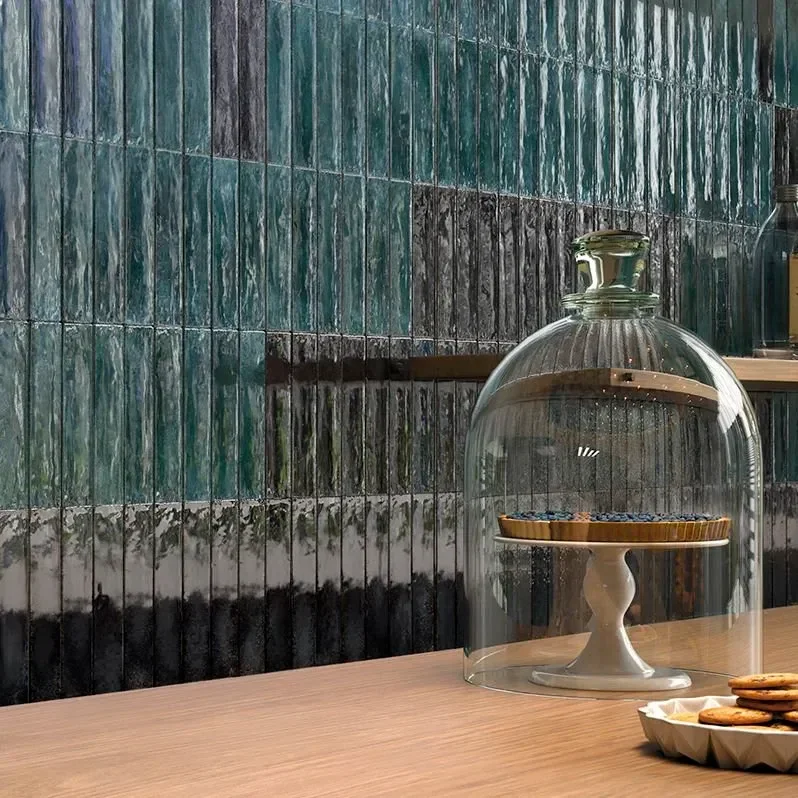 Glassglocke mit Keksen auf einem Kuchenständer, daneben ein Teller mit Keksen, im Hintergrund eine Wand mit grünen Fliesen.