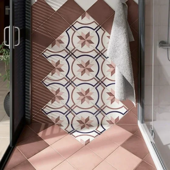 Badezimmerfliesen mit geometrischem Muster, graues Handtuch hängt an der Wand, Badezimmer mit Glasdusche.
