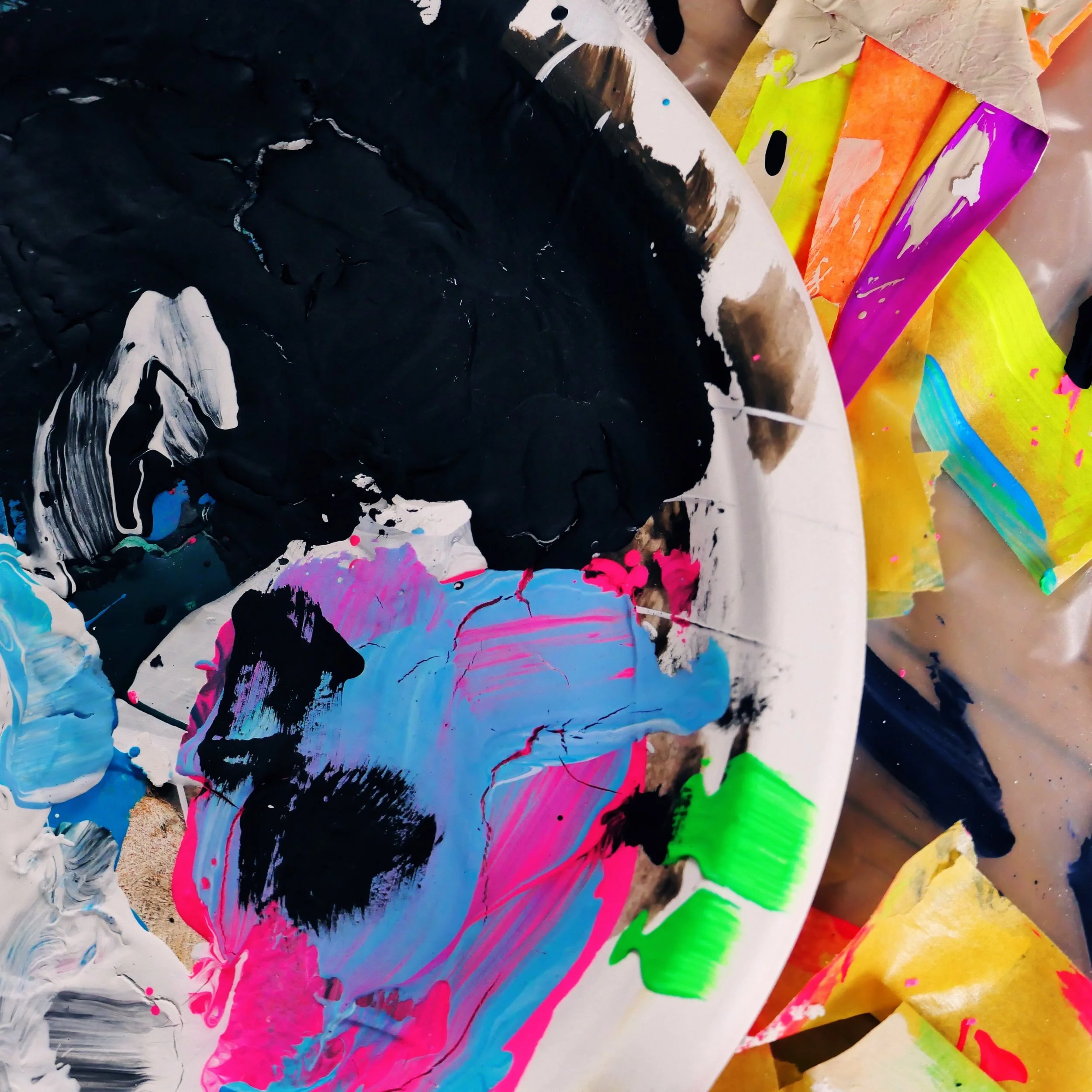 Malerpalette mit bunten Farben und Pinsel, Farbreste und zerknittertes buntes Papier.