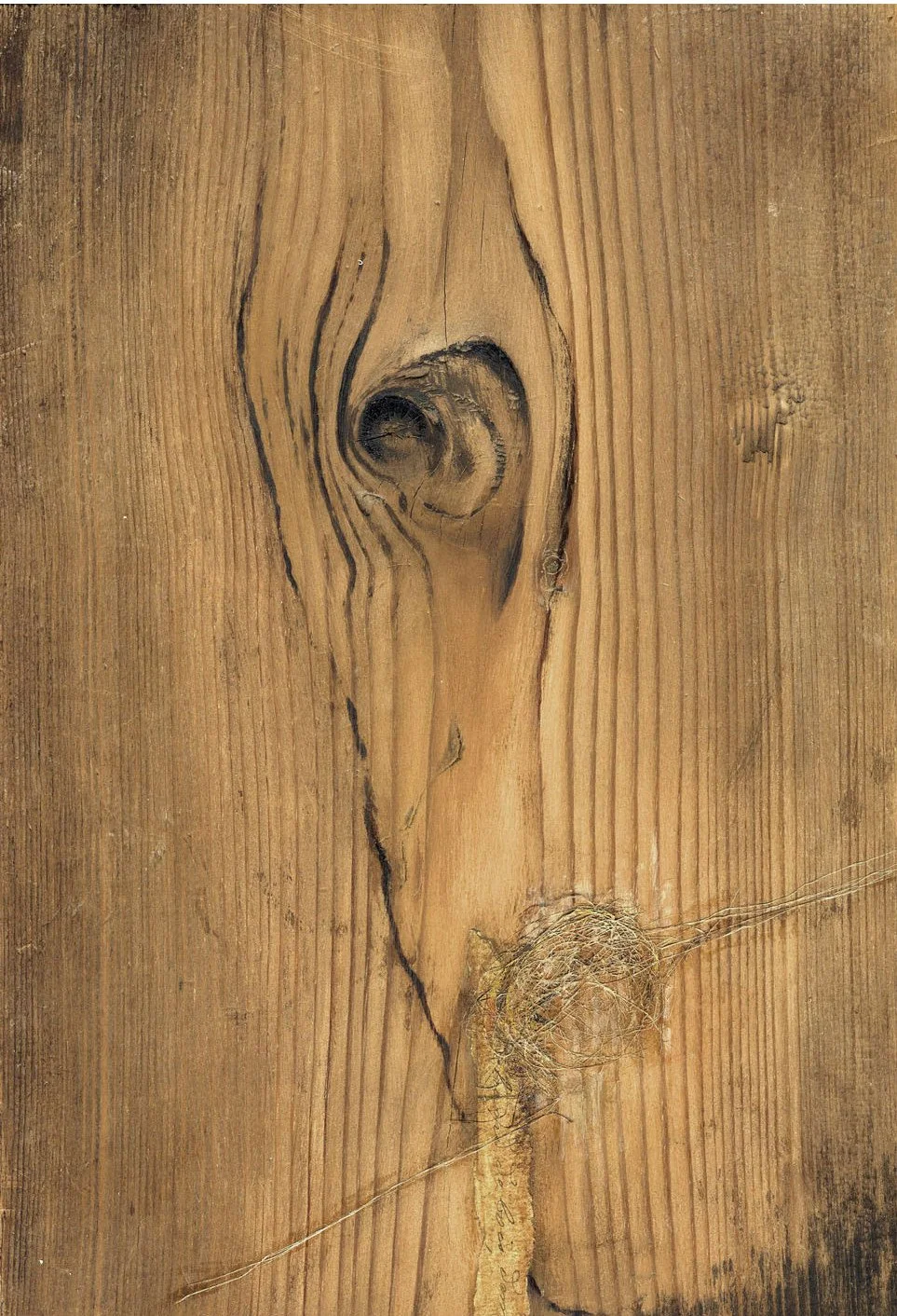 Une surface en bois avec une grande nœud de bois et des grains apparents, montrant des fissures et des imperfections naturelles.