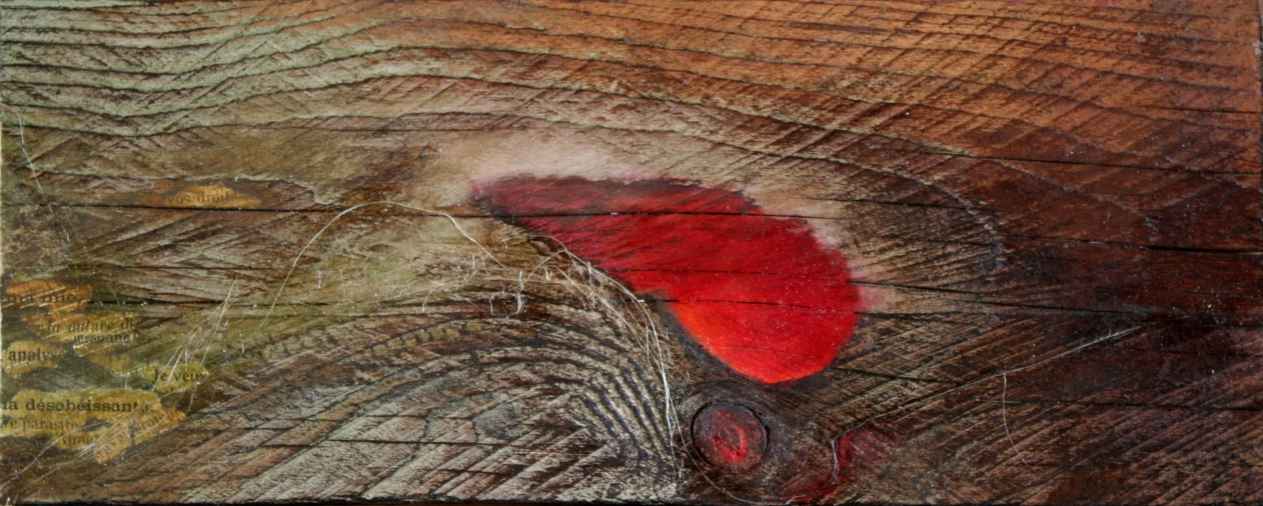 Graffiti sur une surface en bois représentant une tâche rouge avec un cercle en dessous.