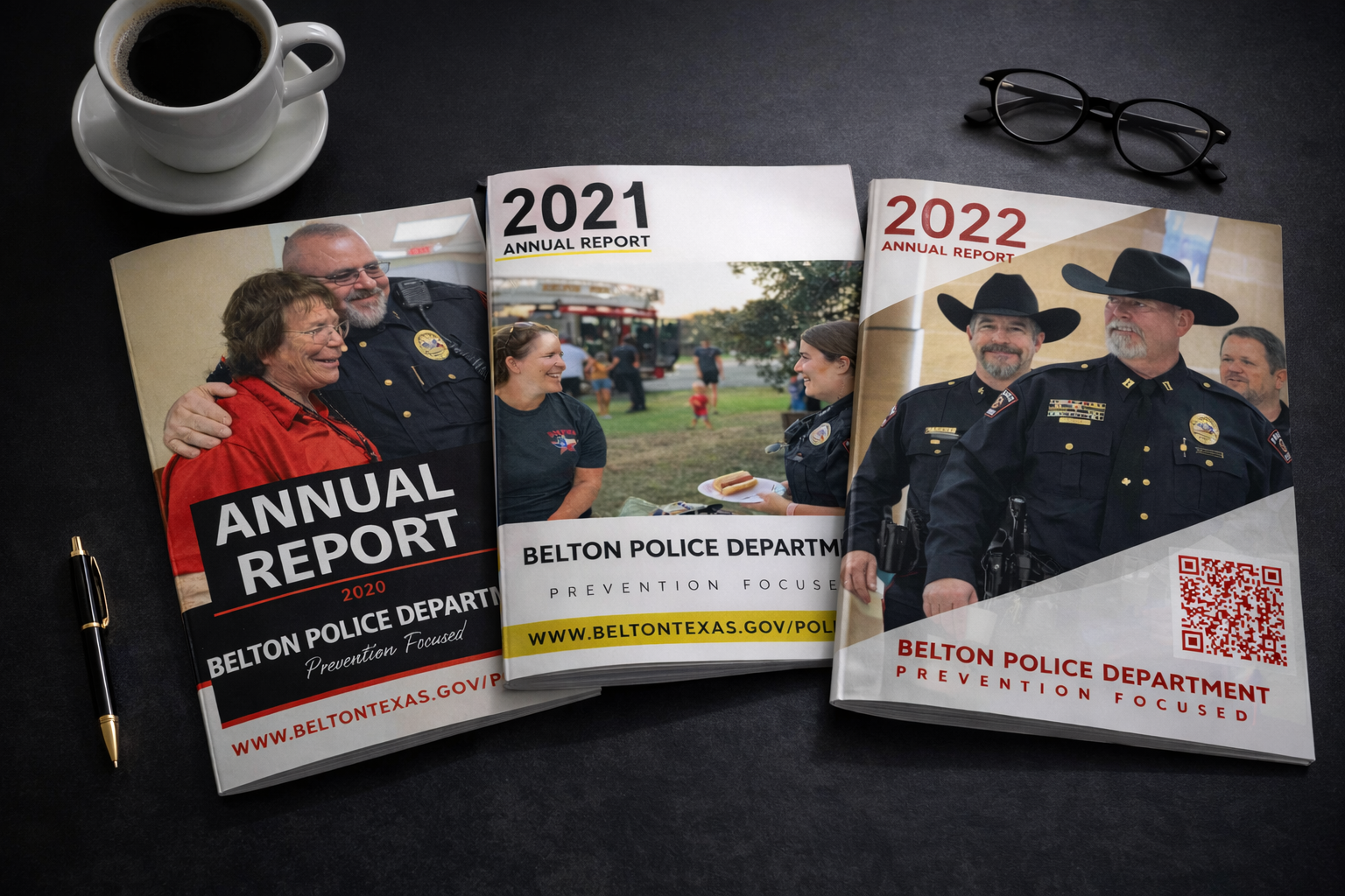Belton Police Department annual report magazine covers from 2020, 2021 and 2022 displayed in chronological order on a desk with a coffee cup and reading glasses.