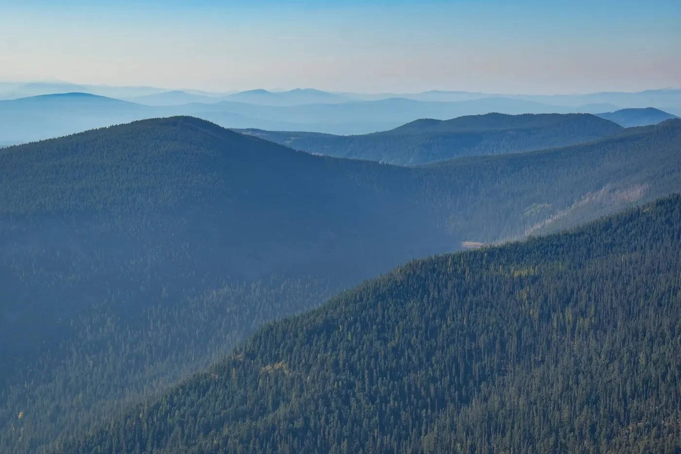 layers of treed mountains with a hazy sky