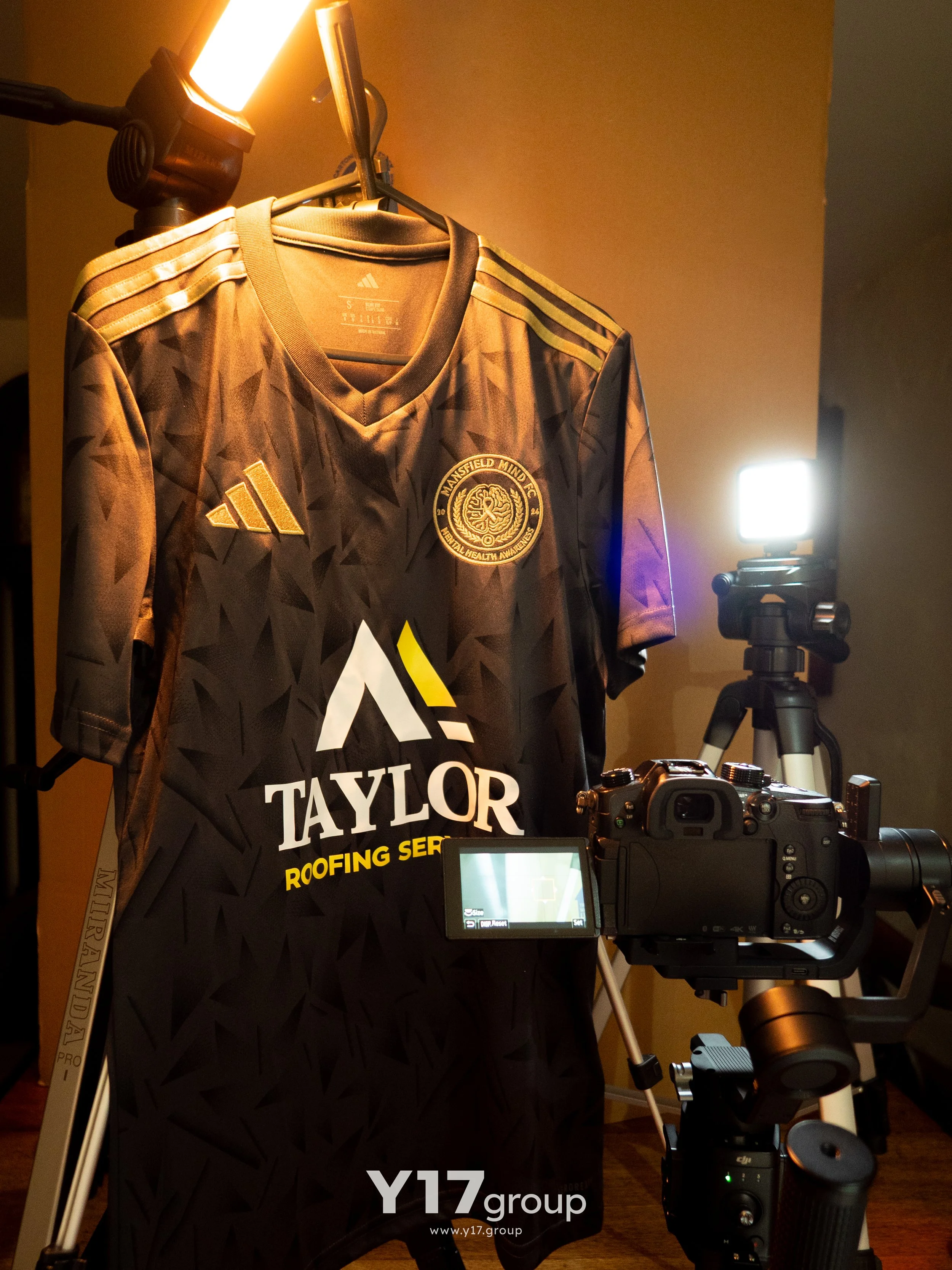 A football shirt illuminated by studio lights, with a camera set up in front of it for photography.