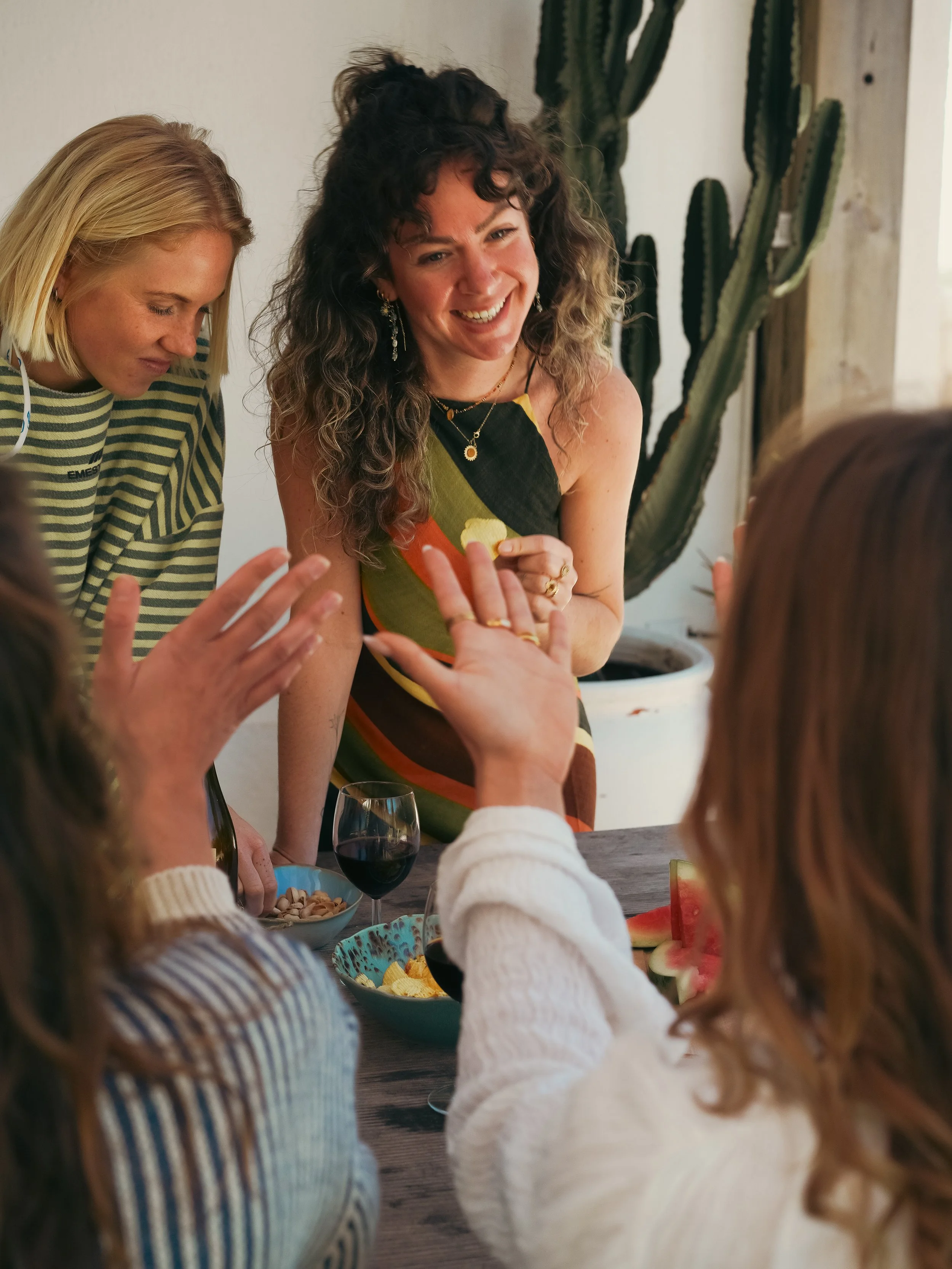 Women enjoying a meal together, with a table full of food and drinks at a surf and yoga retreat.