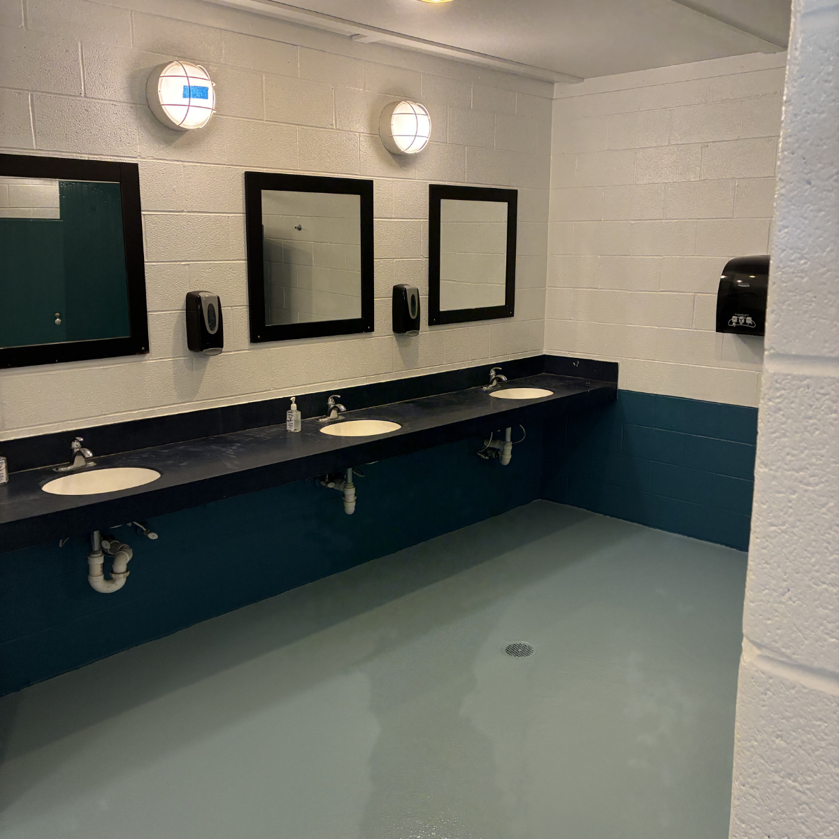 Commercial painters Winchester Virginia – Public restroom with three sinks, two mirrors, soap dispensers, and two wall lights.