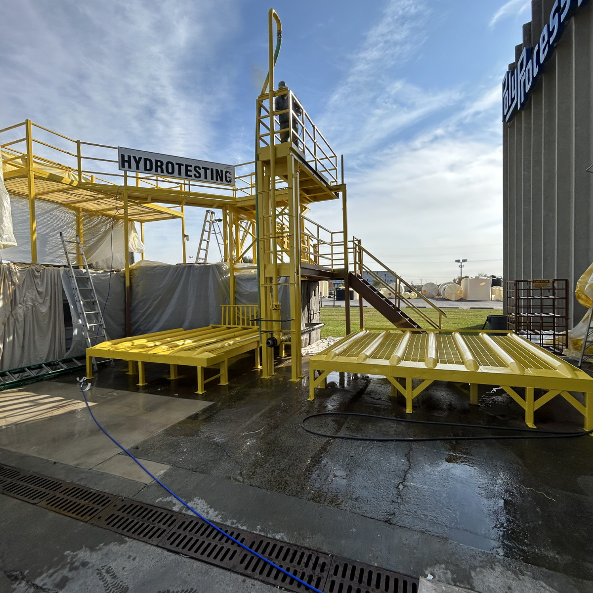 Commercial painting services Winchester Virginia  Industrial hydrotesting platform with yellow safety structures and ladders outdoors under a cloudy sky.