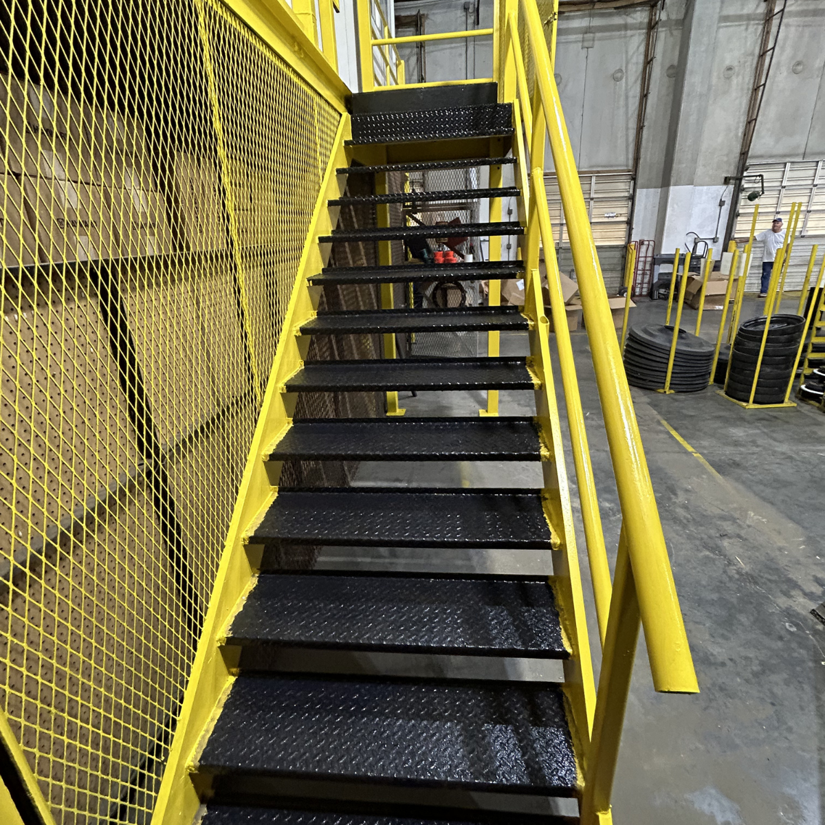 Winchester commercial painters CMT Painting Co. Yellow industrial staircase with black textured steps in a warehouse.