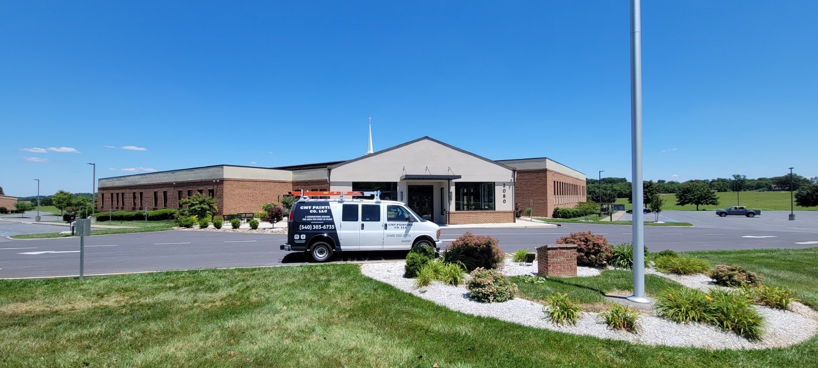 CMT Painting Co. commercial painting Northern Virginia – A church building with a brick and white facade, a parking lot, and a CMT Painting van parked in front, under a clear blue sky.