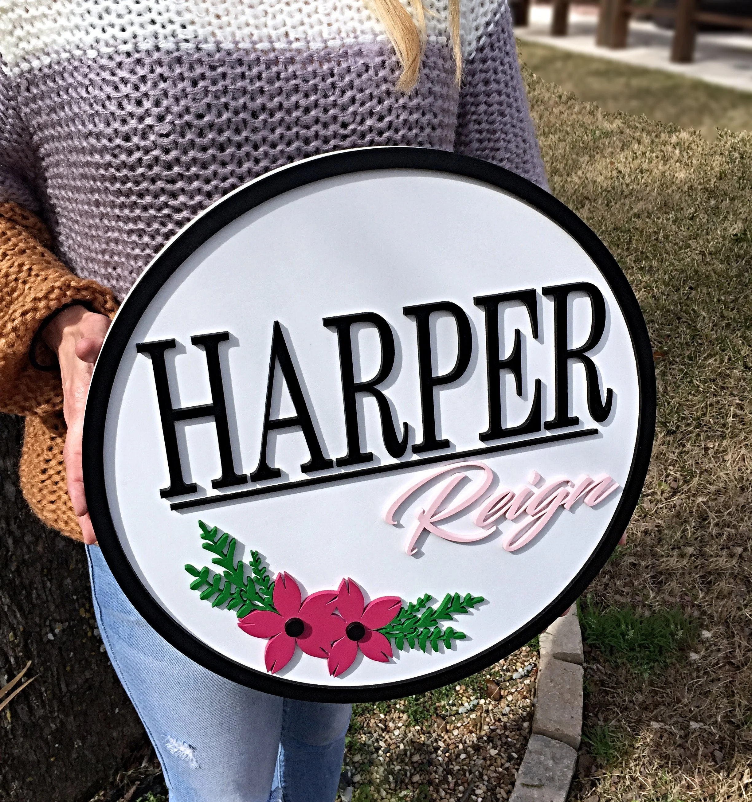 Sign with the text 'Harper Raige' presented in black and pink cursive, decorated with pink flowers and green leaves.
