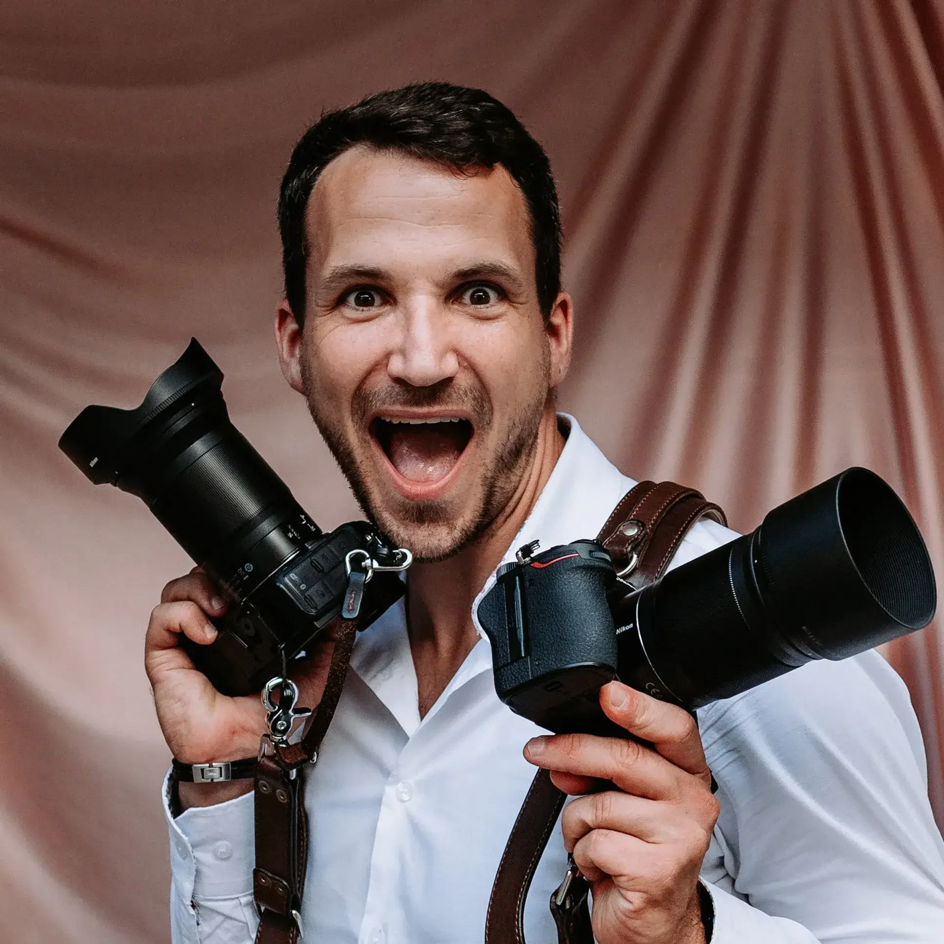 Homme souriant avec deux appareils photo en main