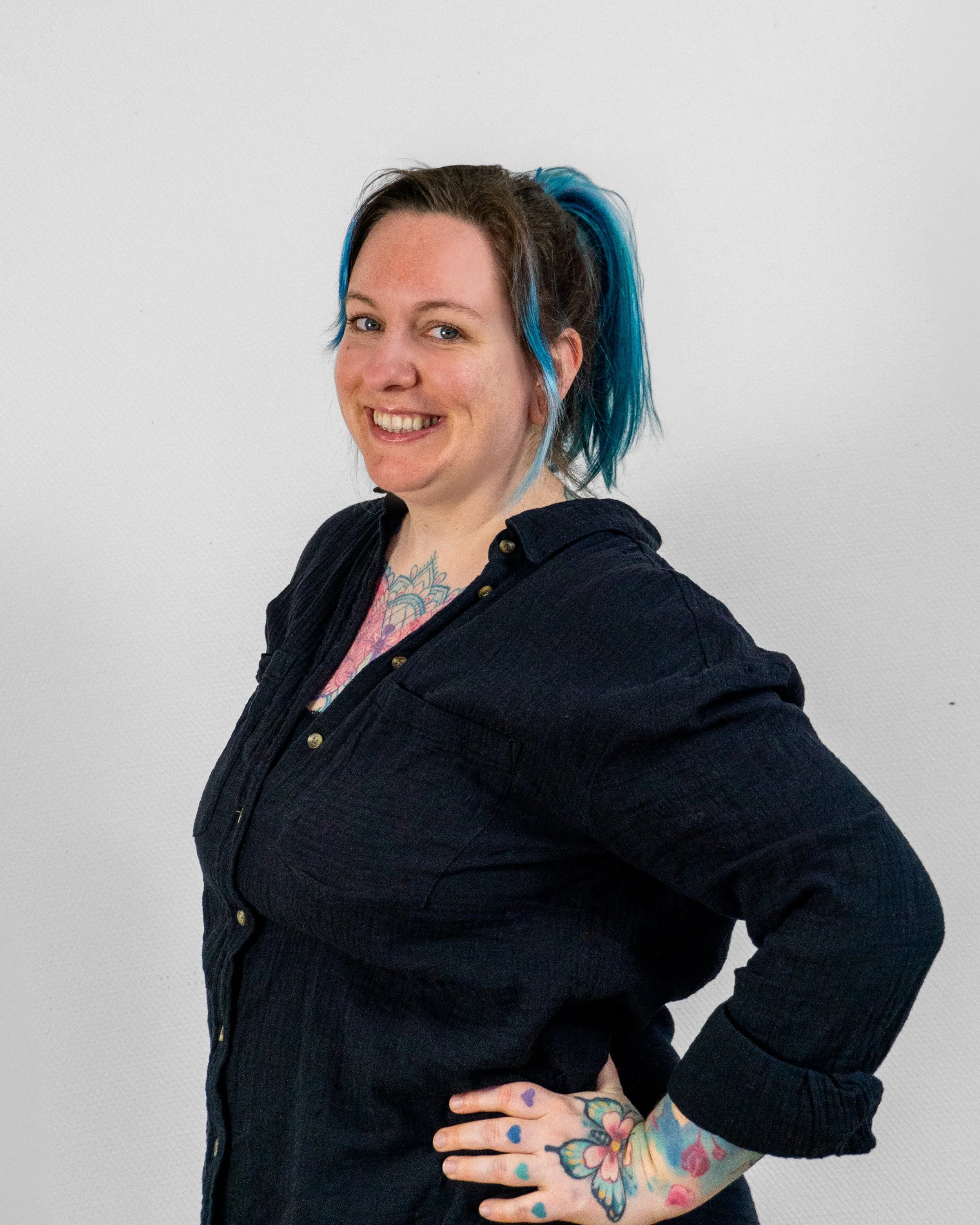 Portrait von Hebamme Meike, sie trägt ein schwarzes Hemd, hat Tattoos und blaue Haare