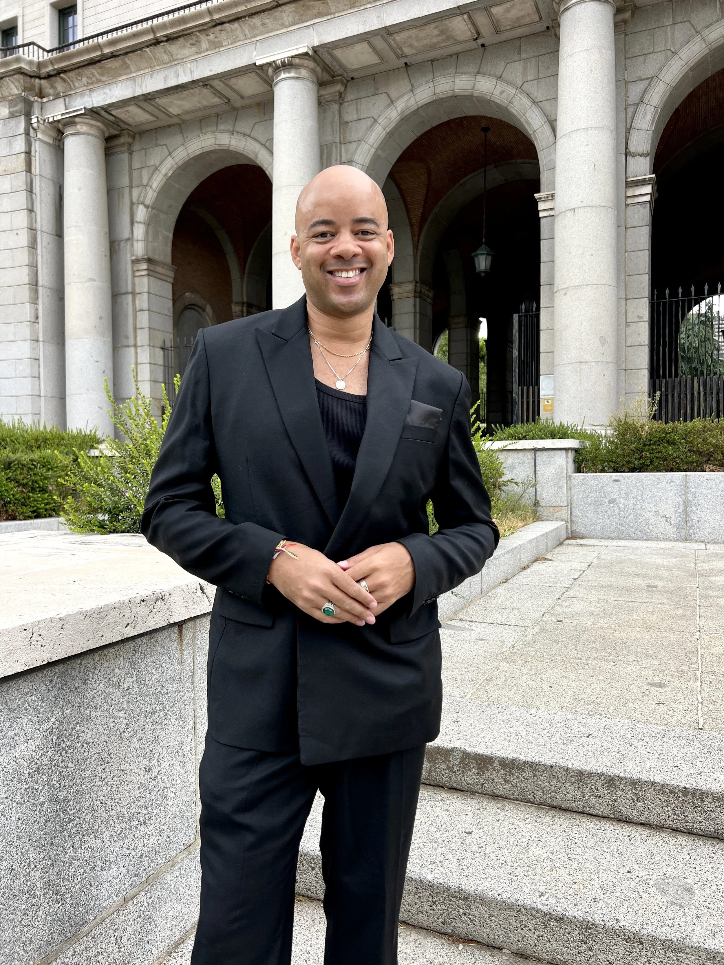 Photo of Ethan Ward in a black suit, standing in front of a stone building with columns