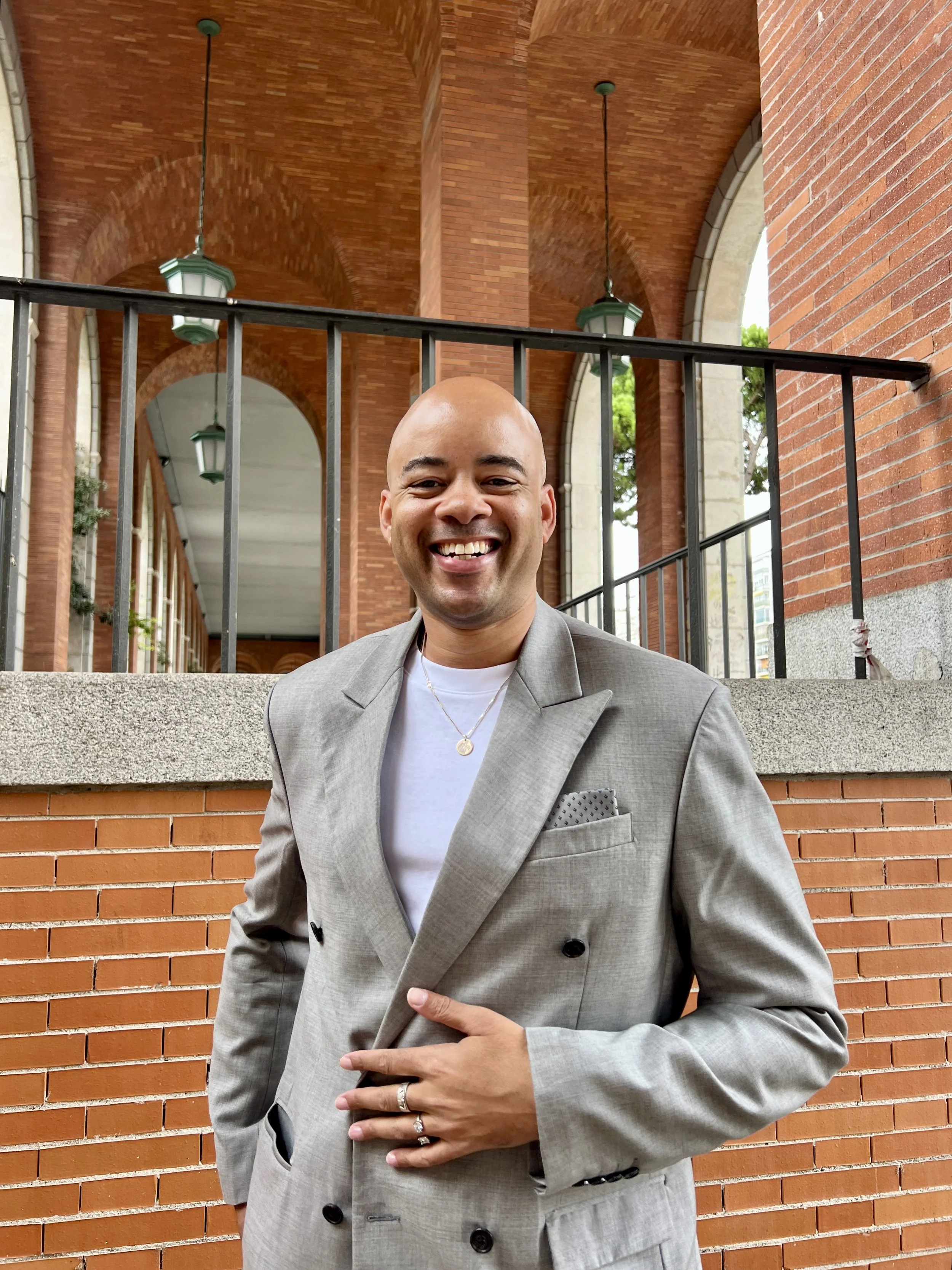 Photo of Ethan Ward in a gray jacket, smiling under brick arches