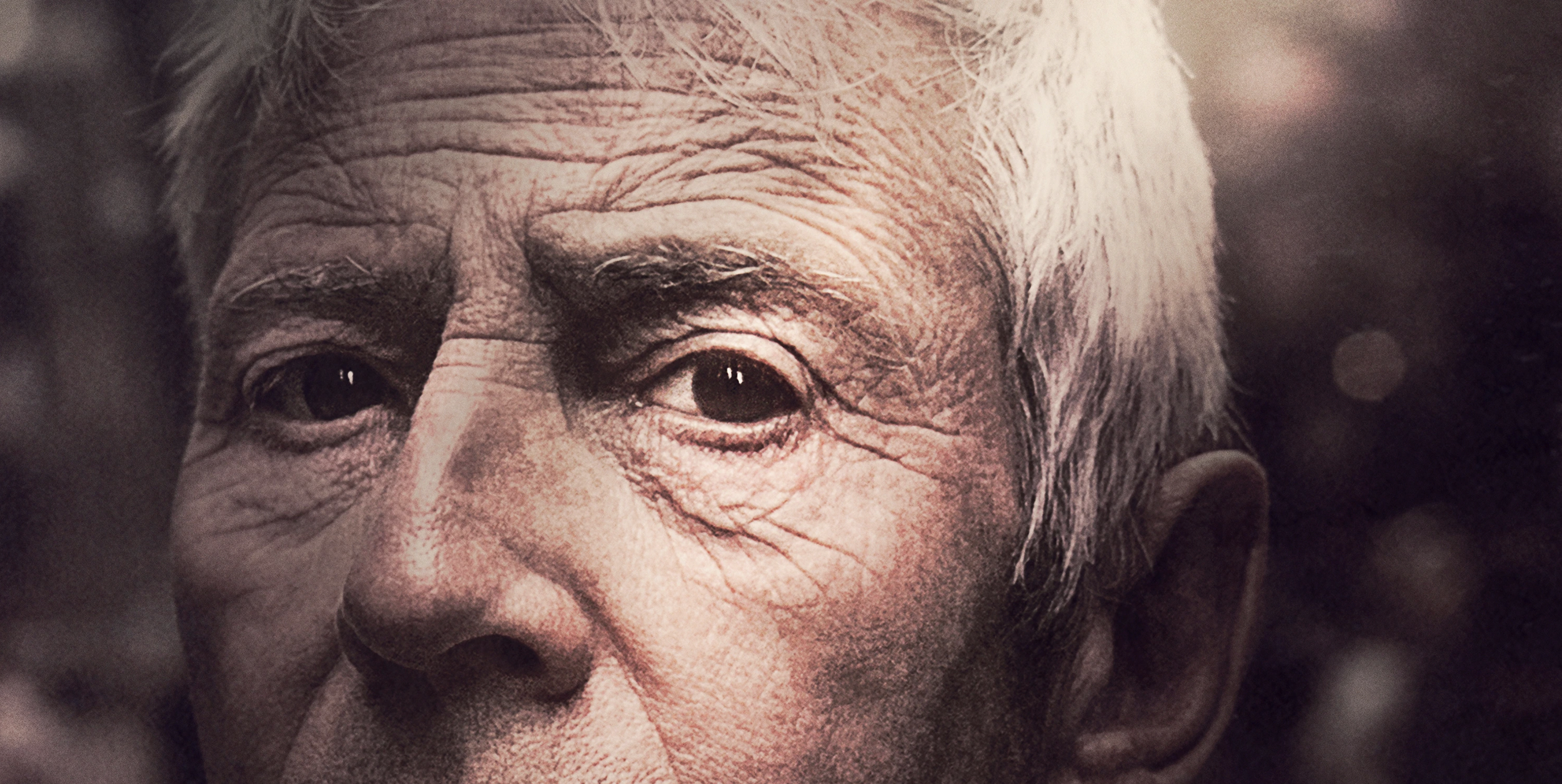 Close-up of an elderly person's face showing detailed wrinkles, with one eye looking forward.