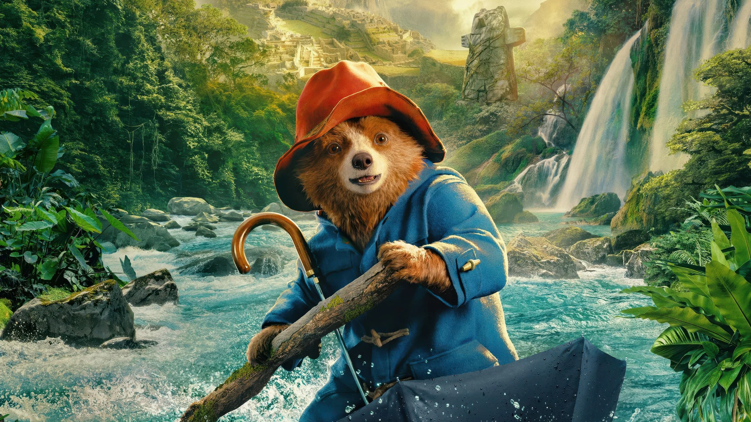 A bear dressed as Paddington in a blue coat and red hat, holding a stick in a canoe on a river surrounded by lush greenery and waterfall in the background.