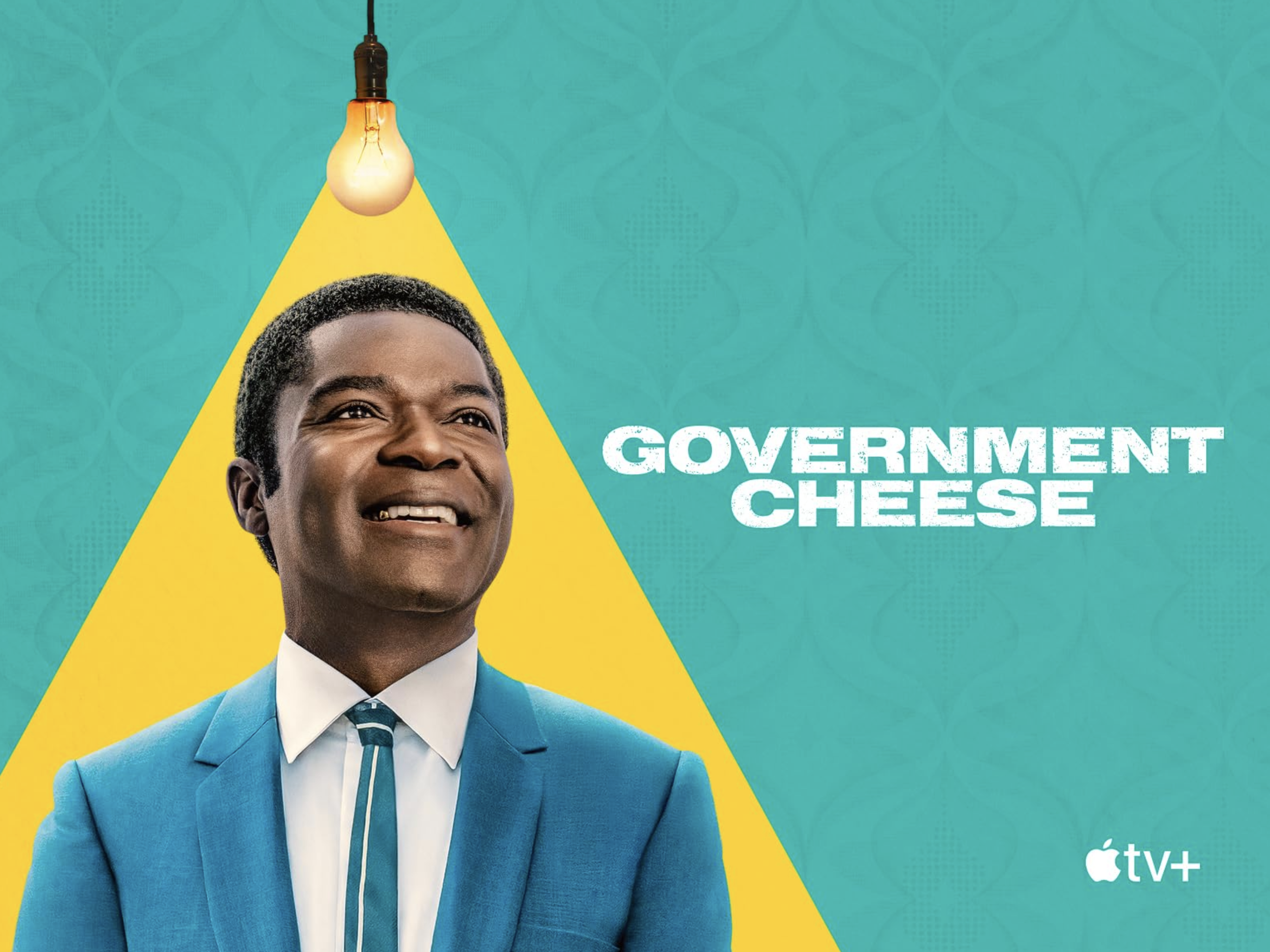 Promotional poster for the TV show 'Government Cheese' on Apple TV+ featuring a smiling man in a blue suit with a yellow triangle background and a hanging light bulb above him.