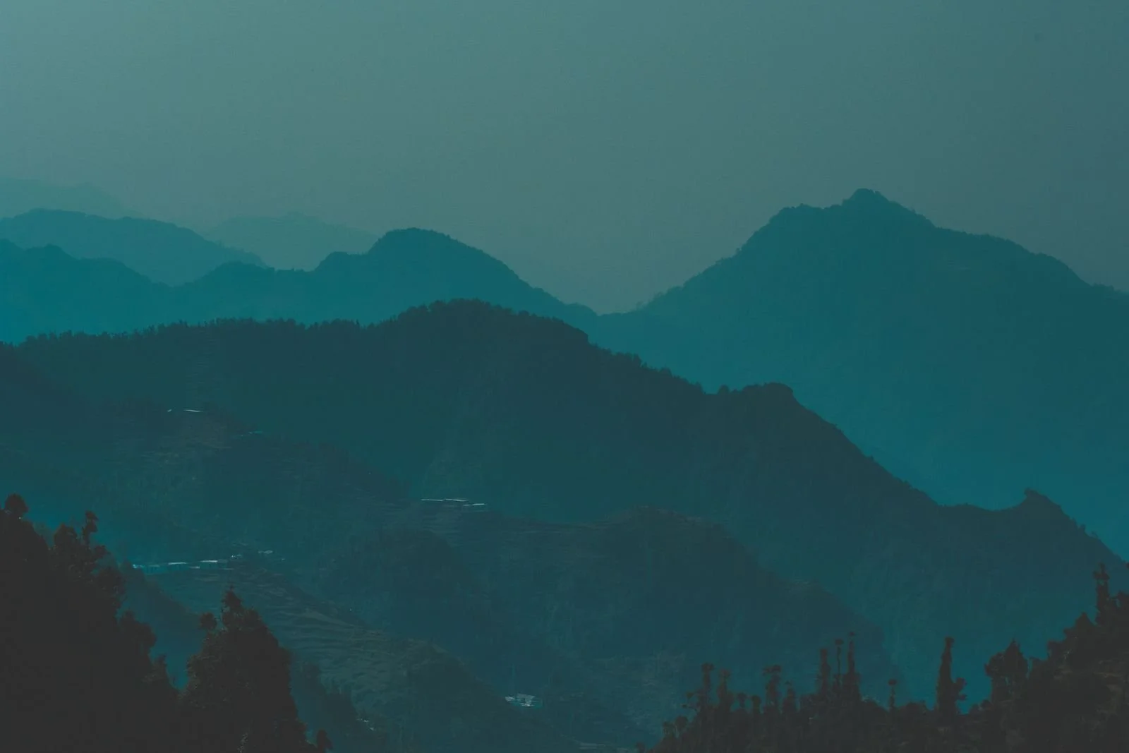 Serene view of misty blue mountains in Dhanolti, India at twilight, capturing nature's tranquility