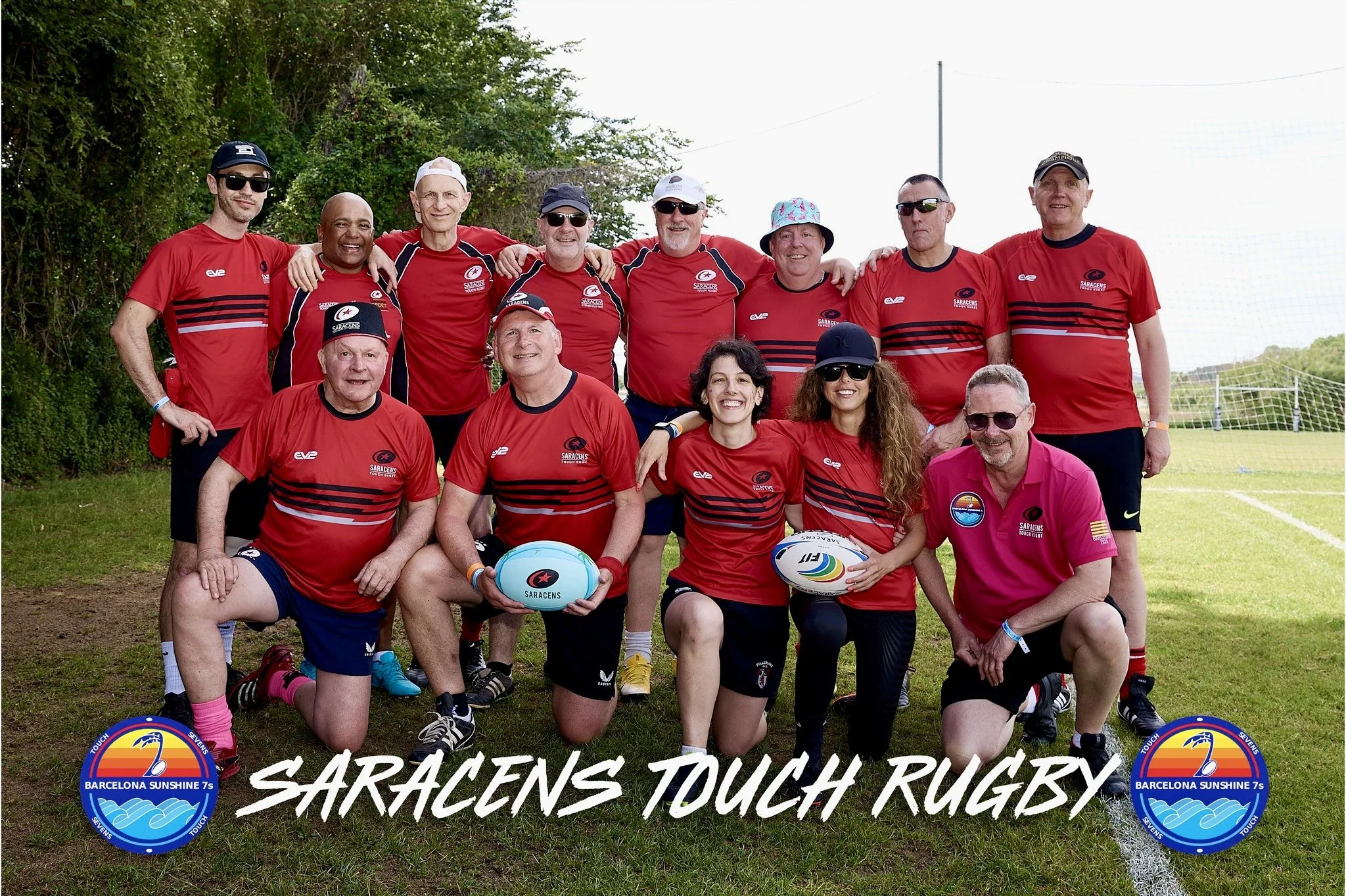 Group of rugby players and coaches wearing red team jerseys with the text 'SARACENS TOUCH RUGBY' and team logos, posing on a grassy field with a goals and trees in the background.