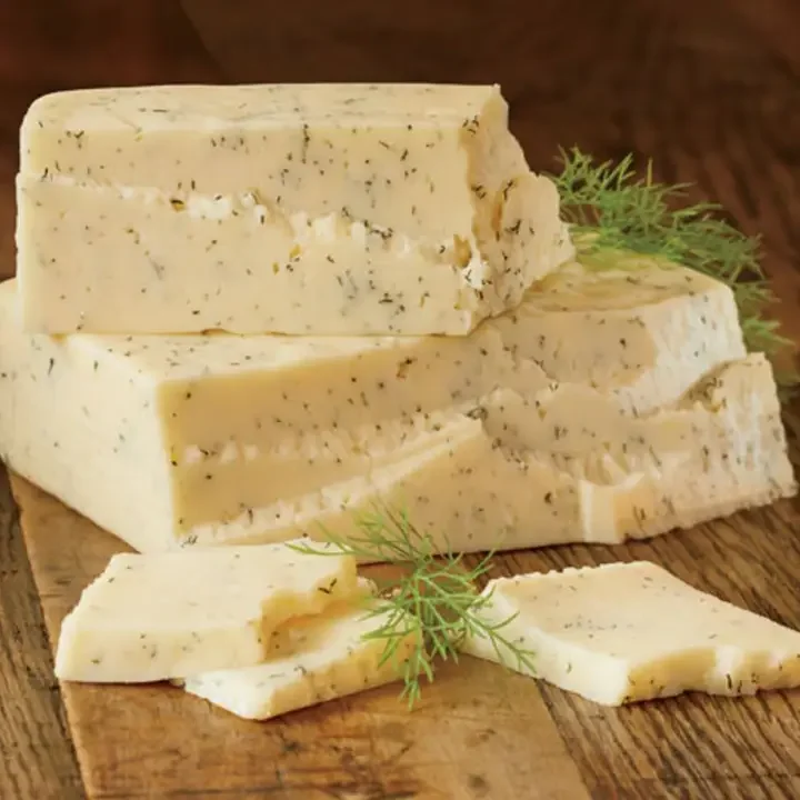 Chunks of blue cheese with herbs on a wooden surface garnished with fresh dill.