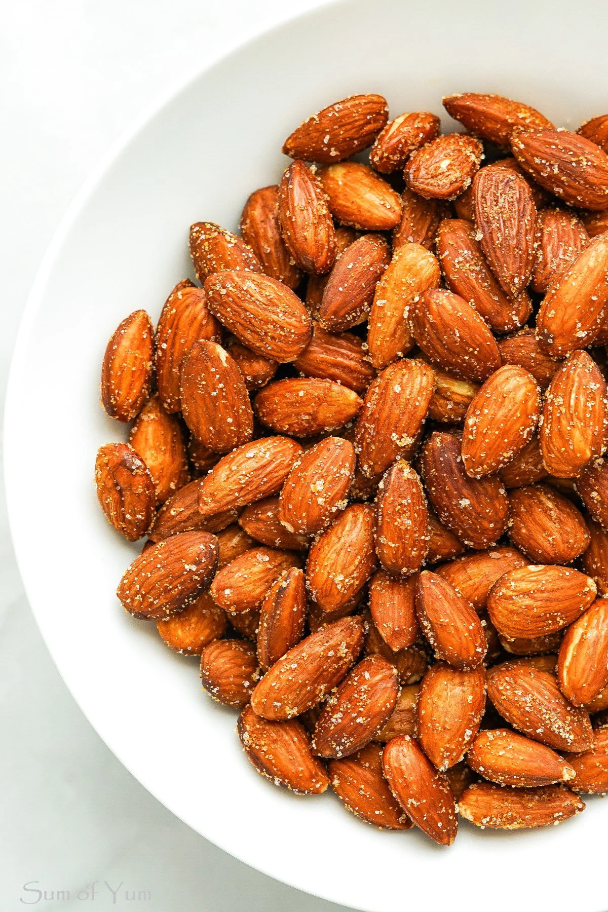A white bowl filled with roasted almonds covered in salt.