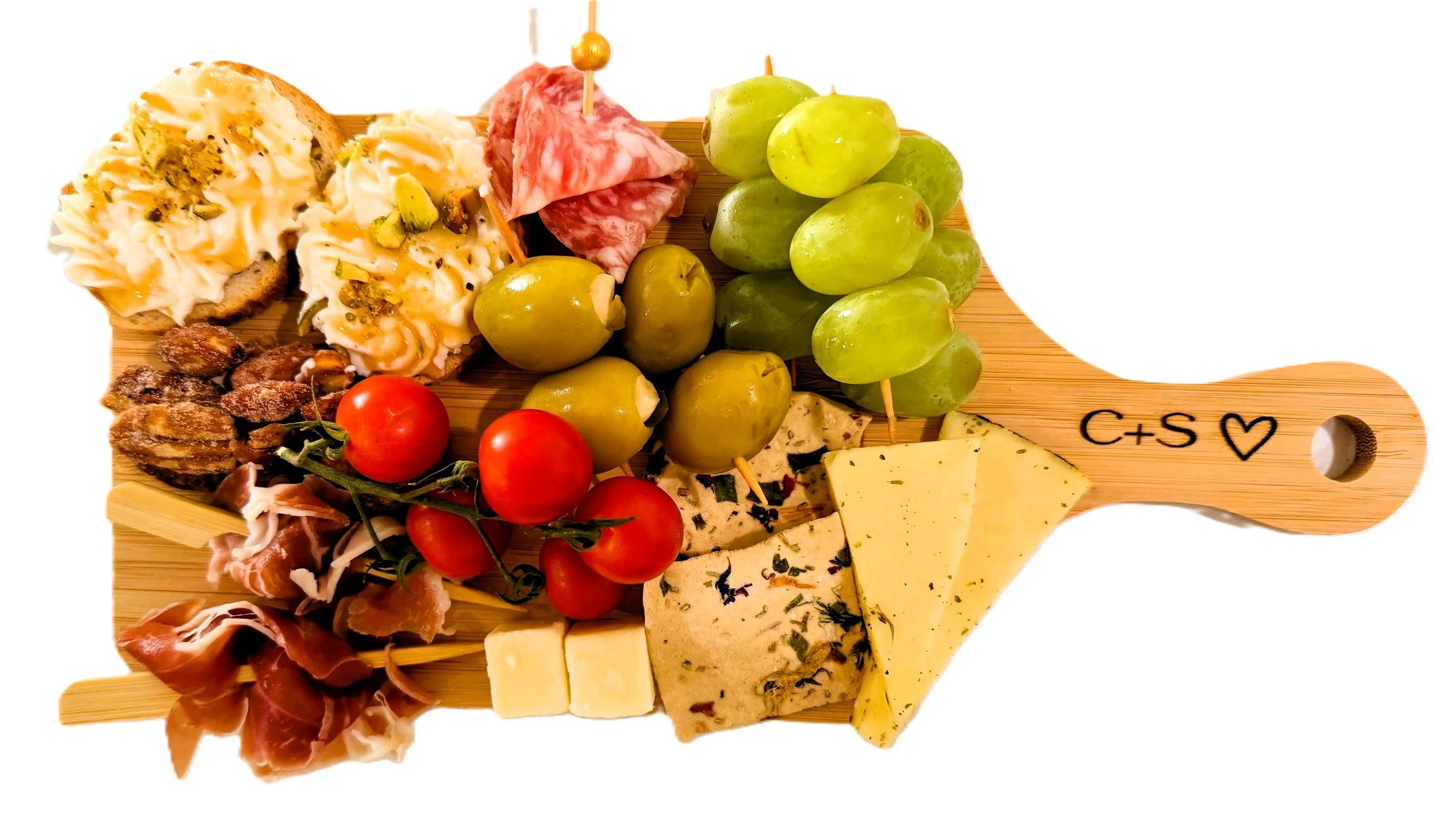 A wooden cheese and charcuterie board with grapes, cherry tomatoes, slices of cheese, cured meats, crackers, and a small tart.
