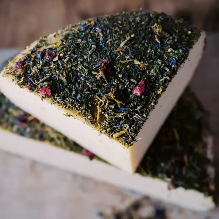 Close-up of a bar of soap topped with dried herbs and flower petals.