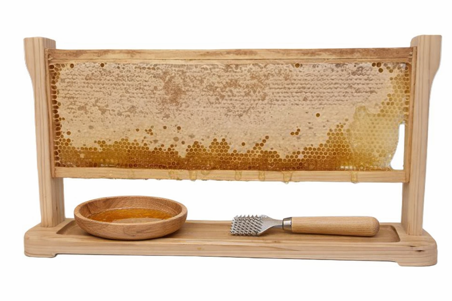 A wooden honey display case with a honeycomb frame, a small wooden bowl filled with honey, and a honeycomb slicer tool on a wooden base.