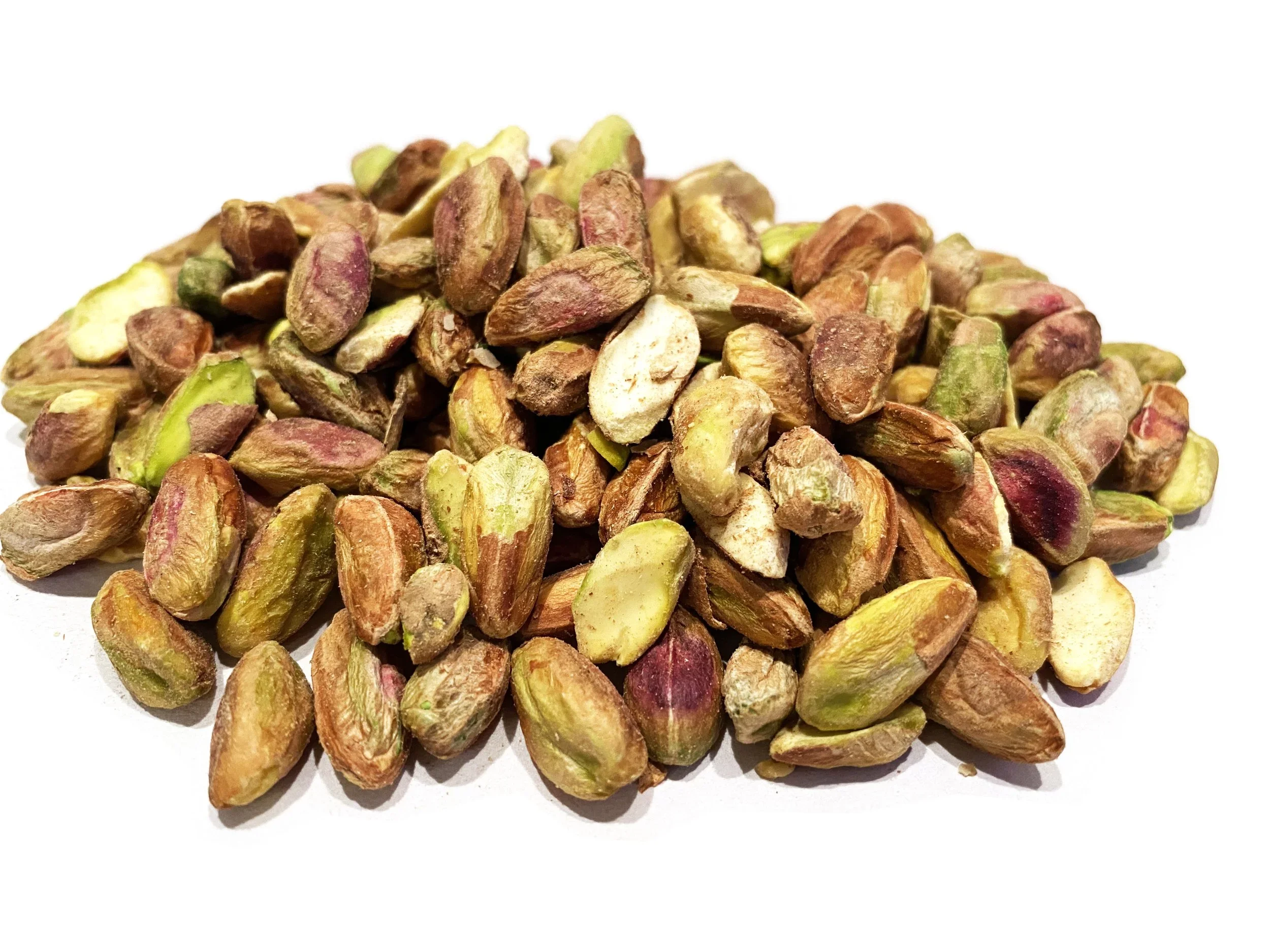 A pile of shelled pistachio nuts with some shells missing, showing their green and purple kernels.