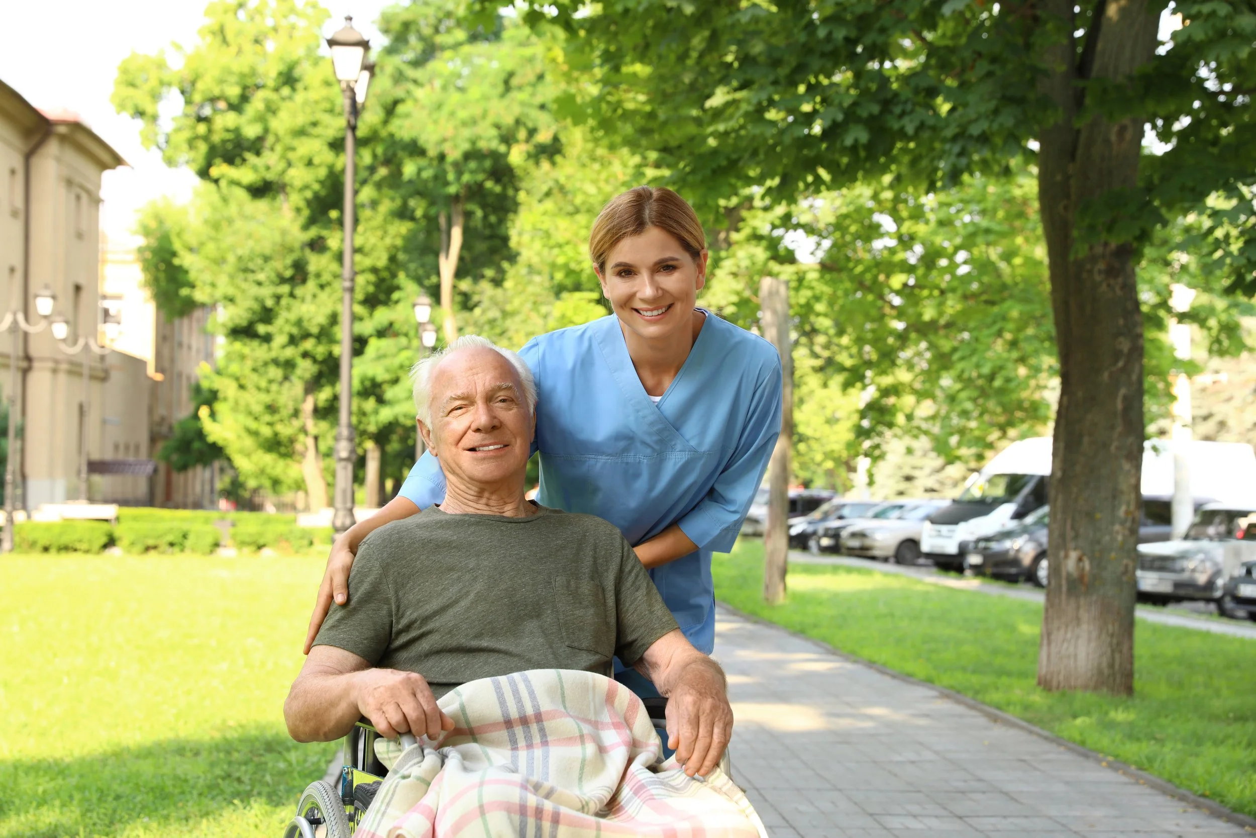 Senior man in a wheelchair enjoying time outdoors with a caregiver.