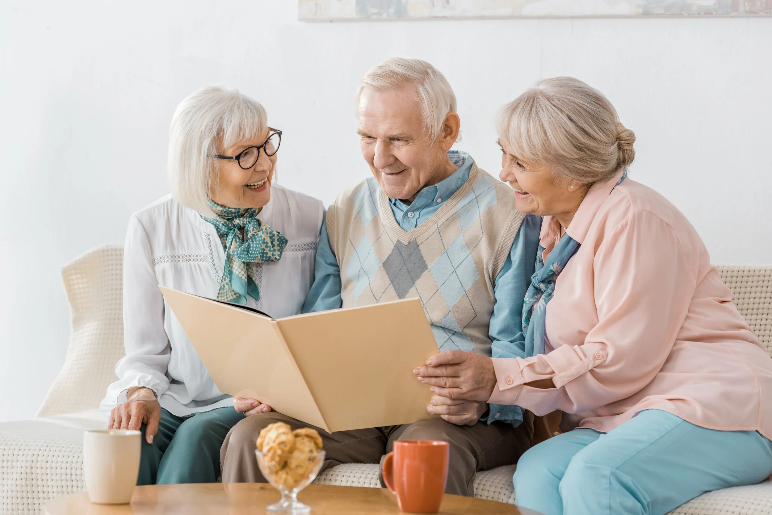 Three seniors looking through a photo album together in a retirement residence.