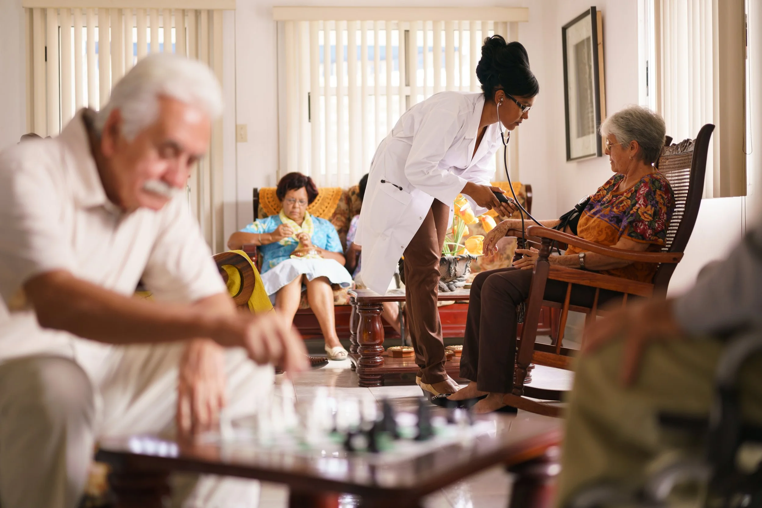Health professional checking a senior woman’s blood pressure in a residential care setting.